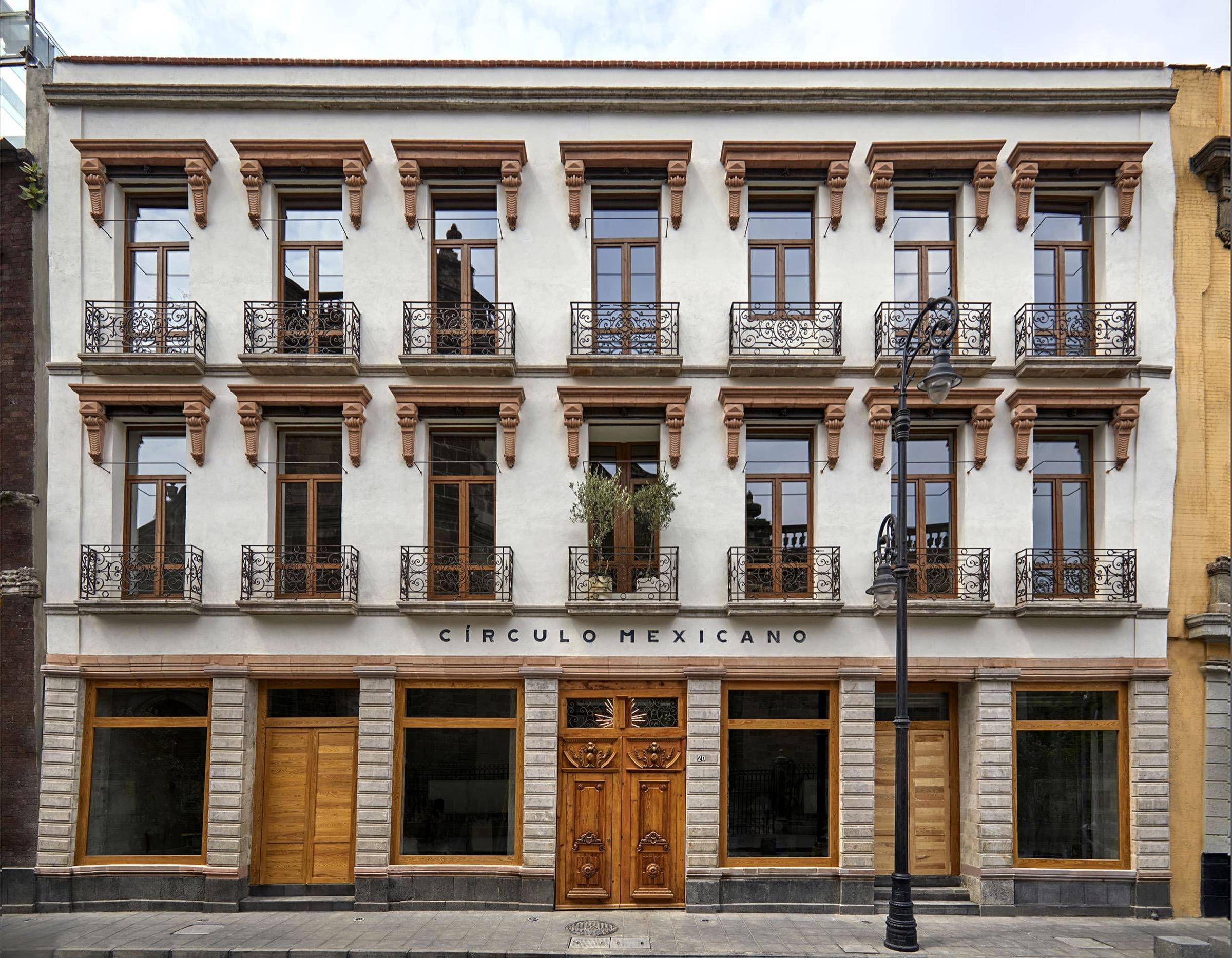 A three-storey colonial-era building facade in white and ochre, with wrought-iron balconies, shuttered windows, and a carved wooden double door, labelled Circulo Mexicano, on a city street.