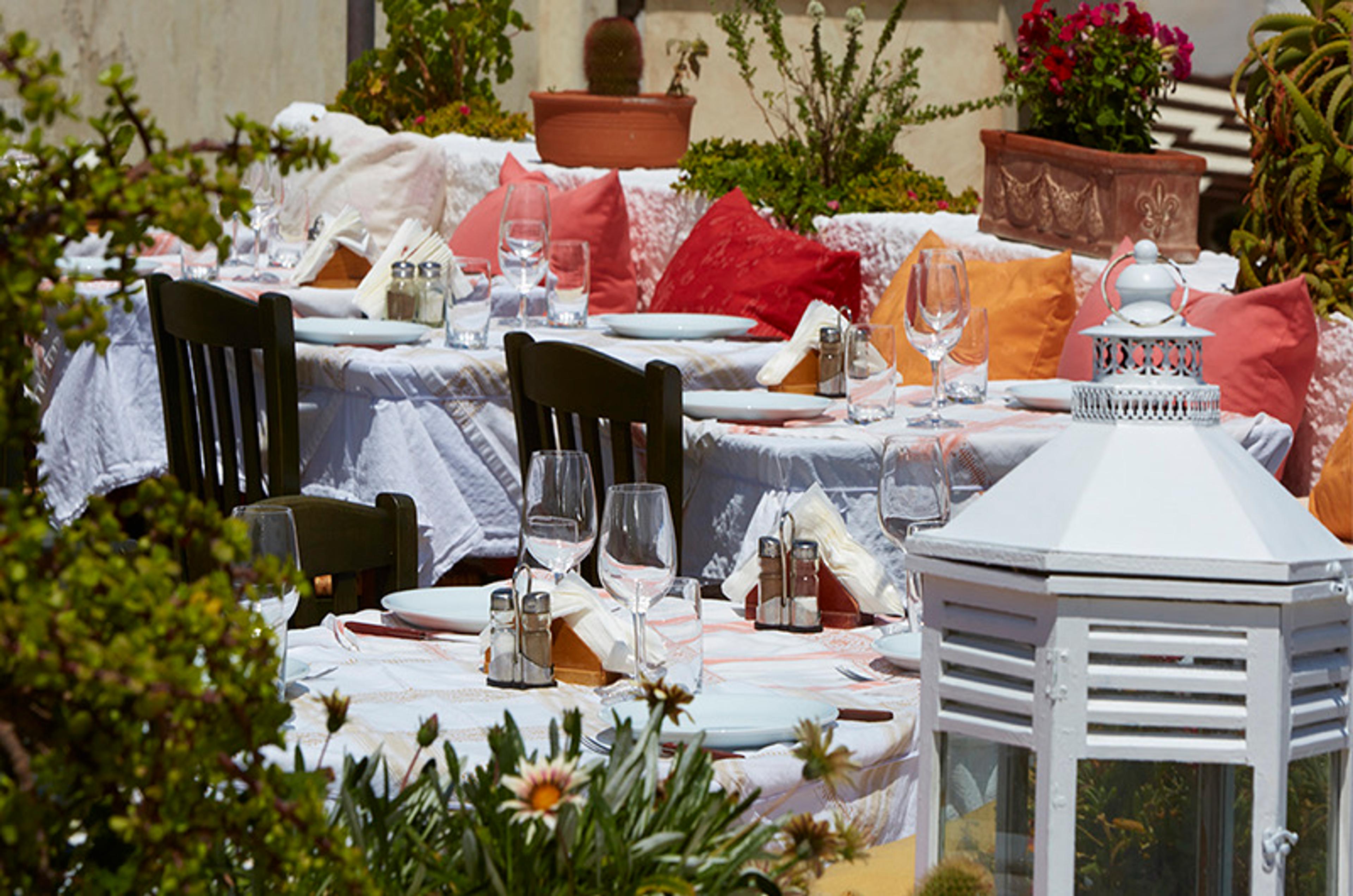 Tables laid with white cloths in a courtyard full of flowers