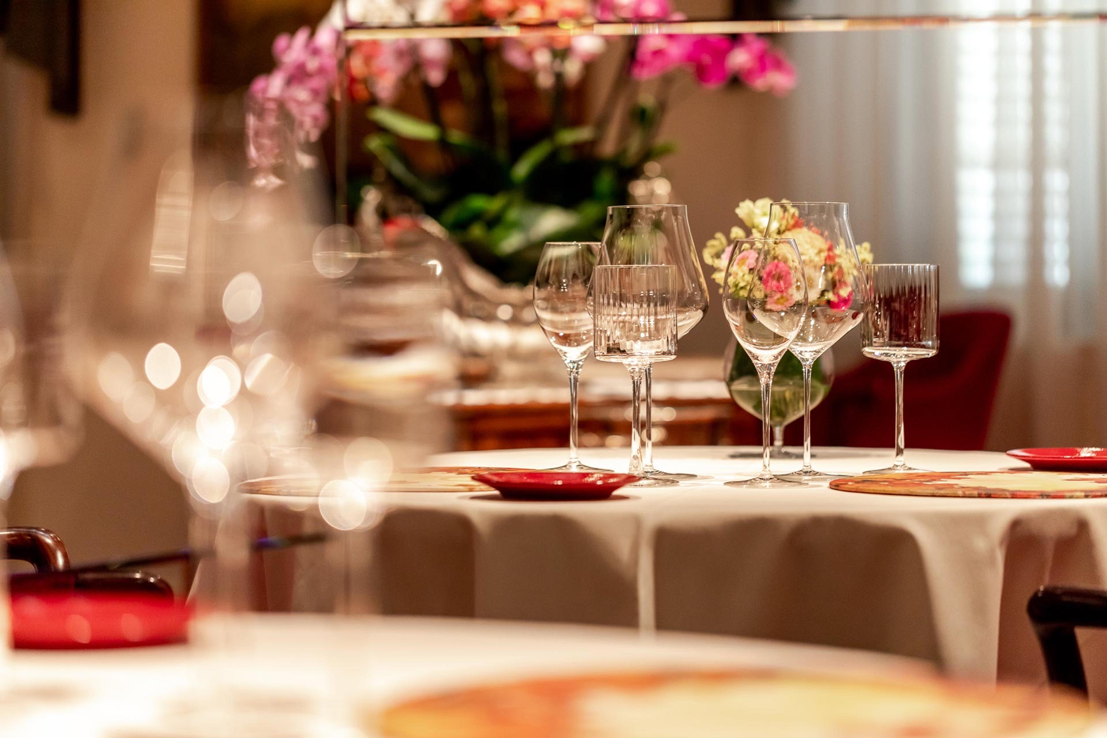 The dining room at Enoteca Pinchiorri, glasses laid on white cloths under flowers