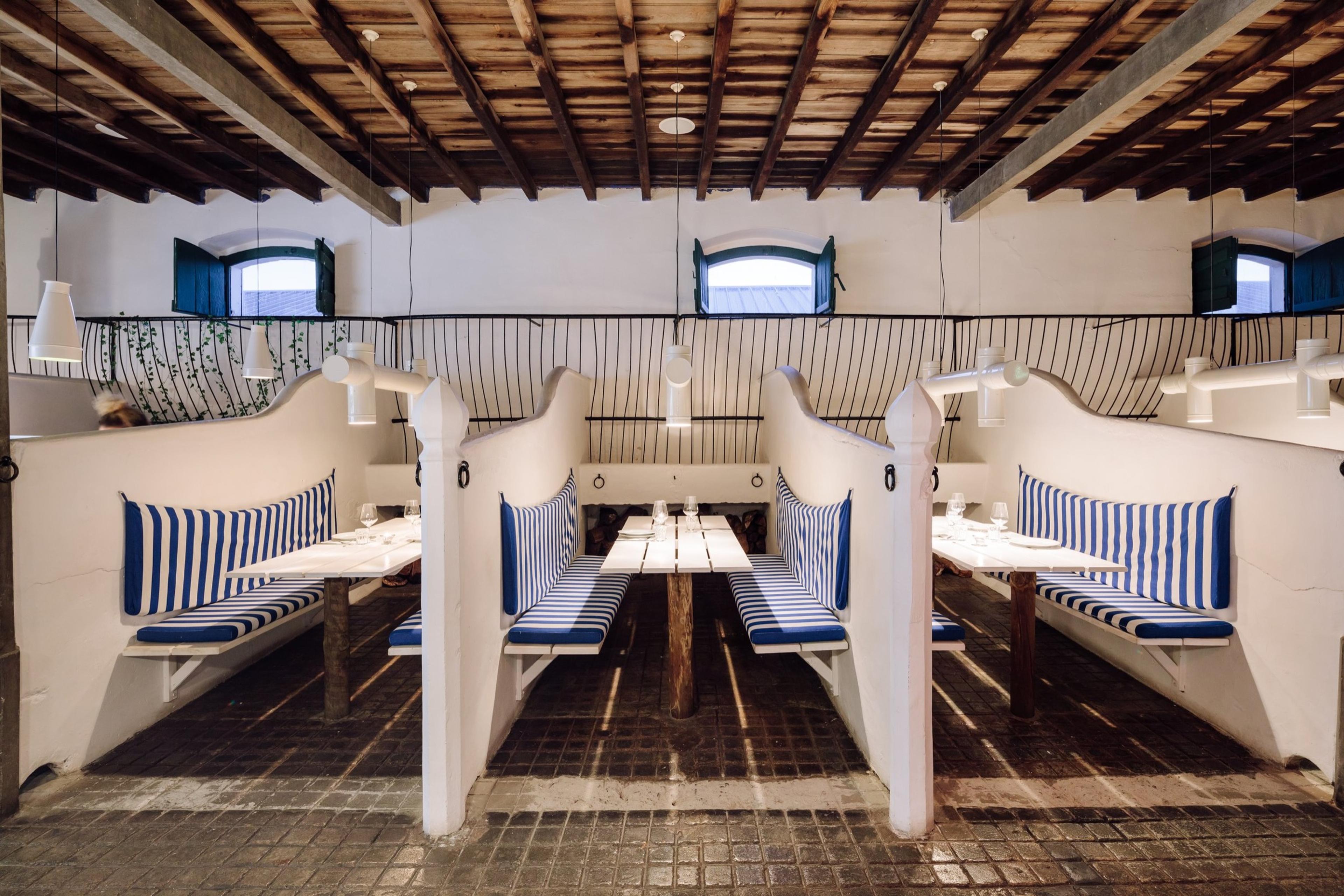 White curved booths with striped cushions under a dark timber ceiling in a converted stable