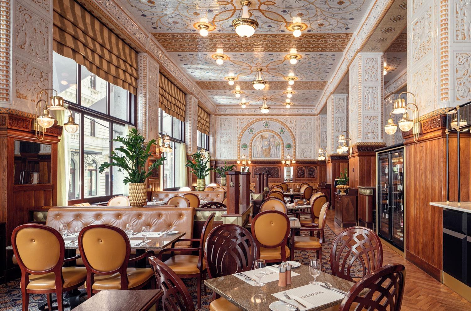 The tiled dining room of Café Imperial, set tables under its decorated ceiling
