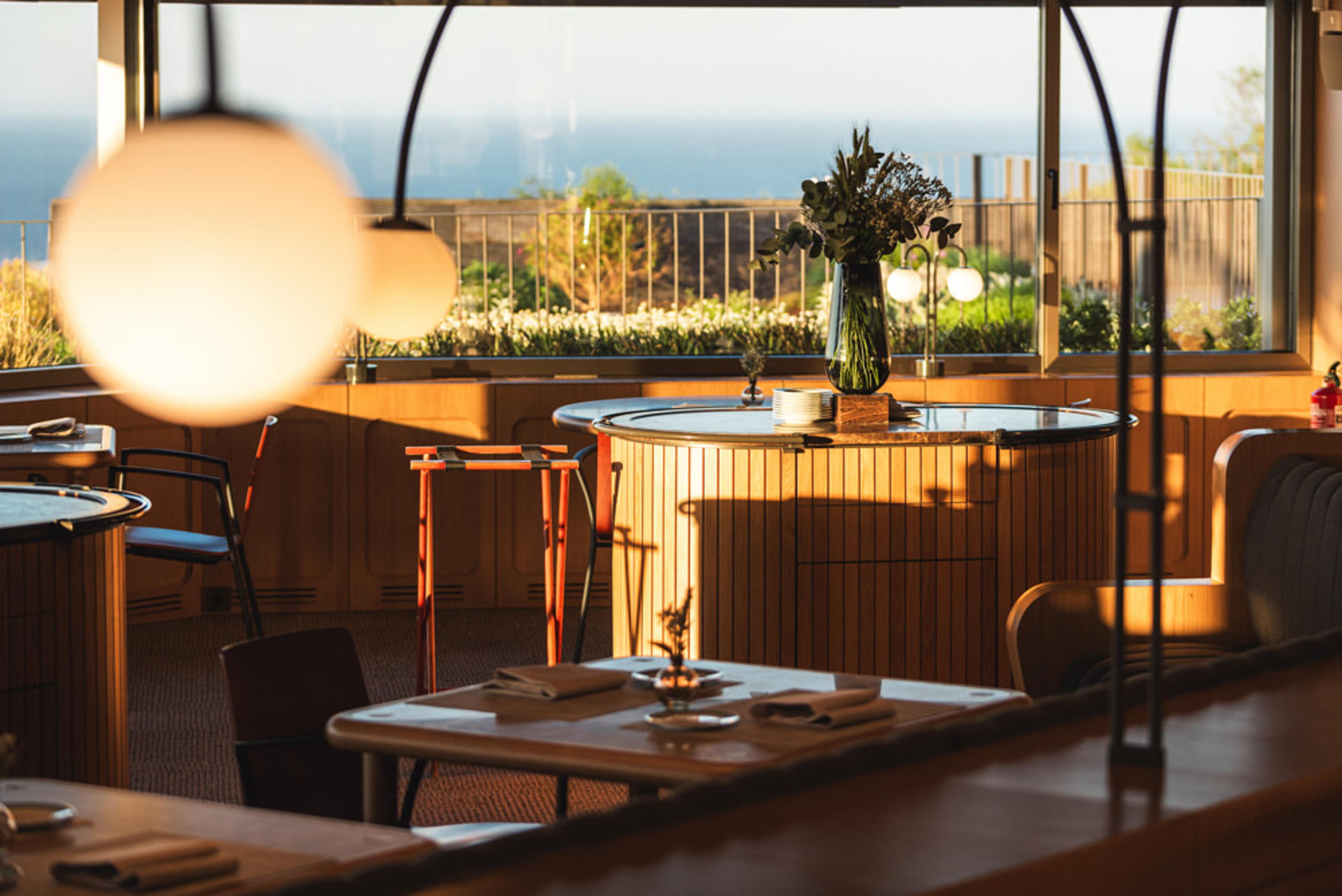 Akelarre's dining room on Monte Igueldo at dusk, tables under hanging lamps before the windows