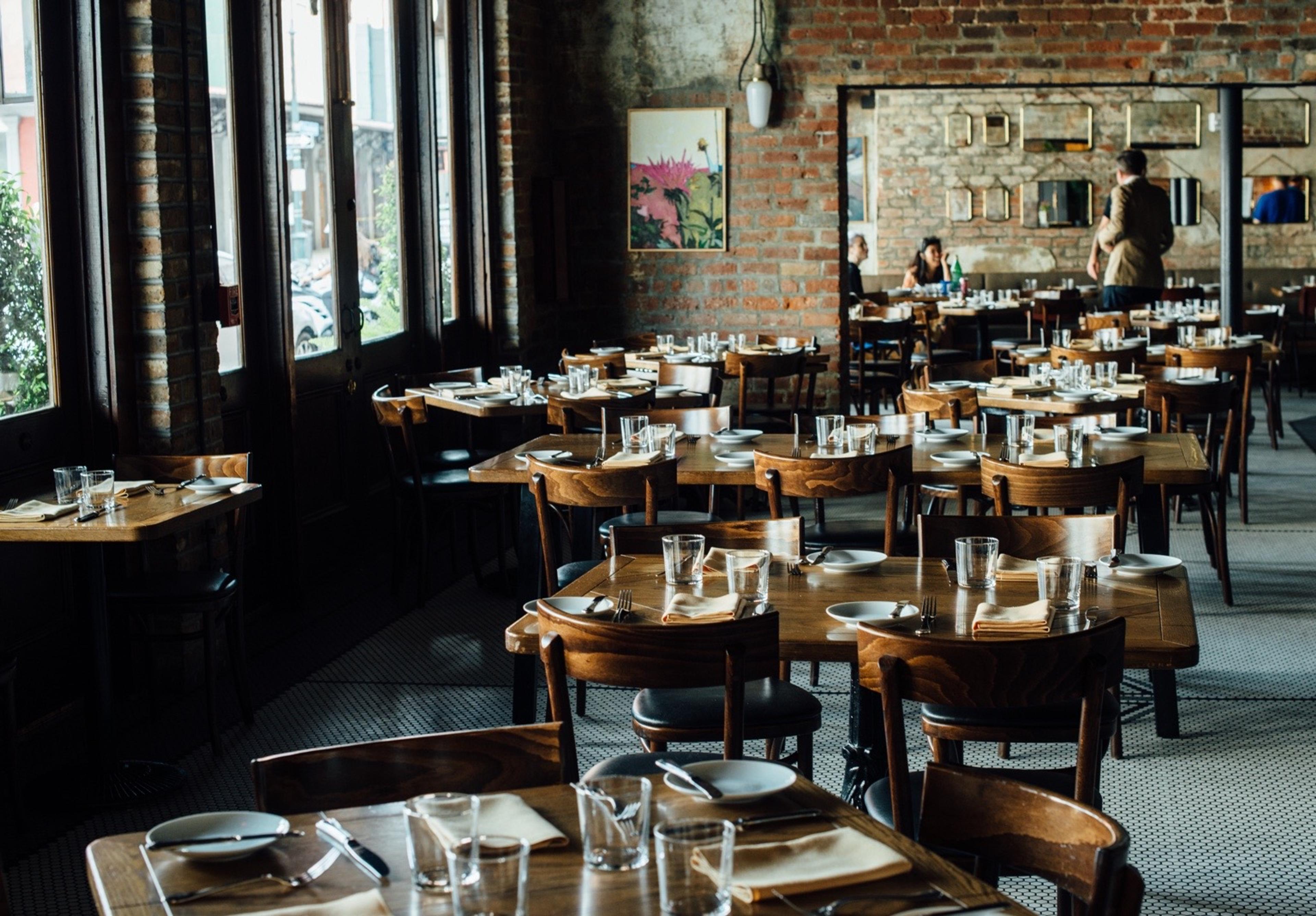 Rows of tables in a dining room with bare brick walls