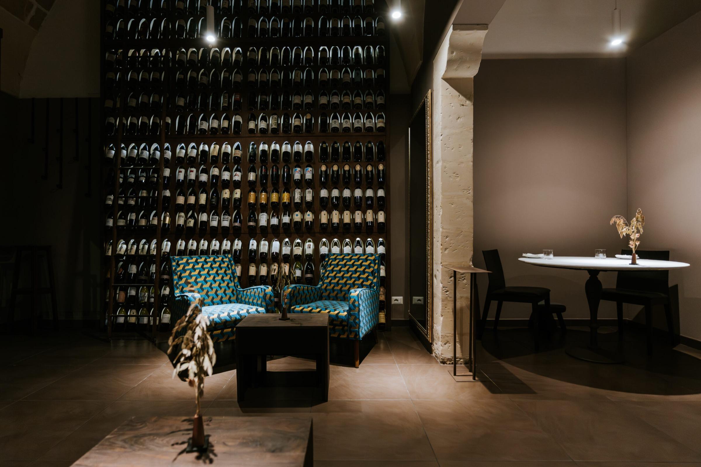 Primo's dining room in low light, a wall of wine bottles behind velvet seats