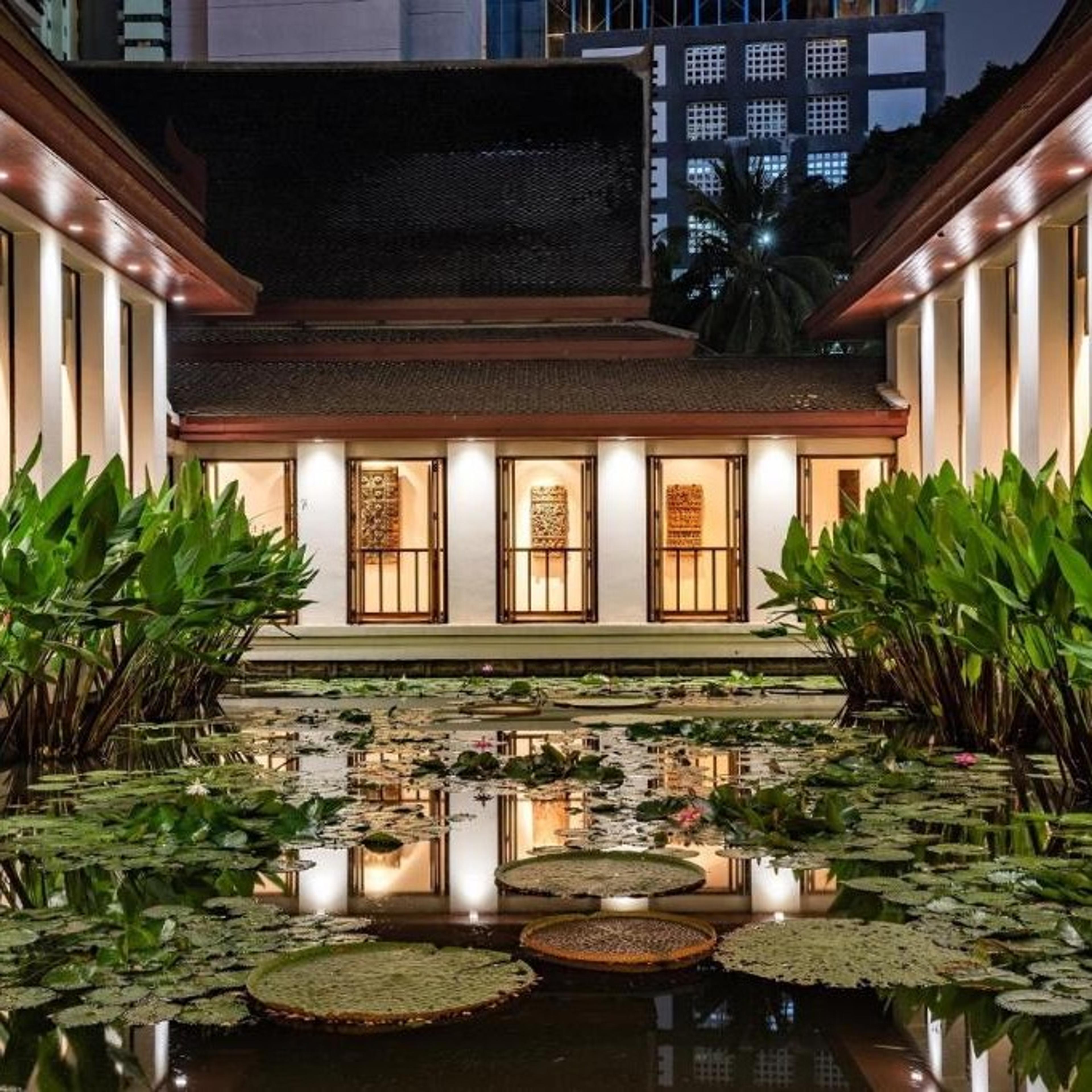 A pavilion lit at night over a lotus pond
