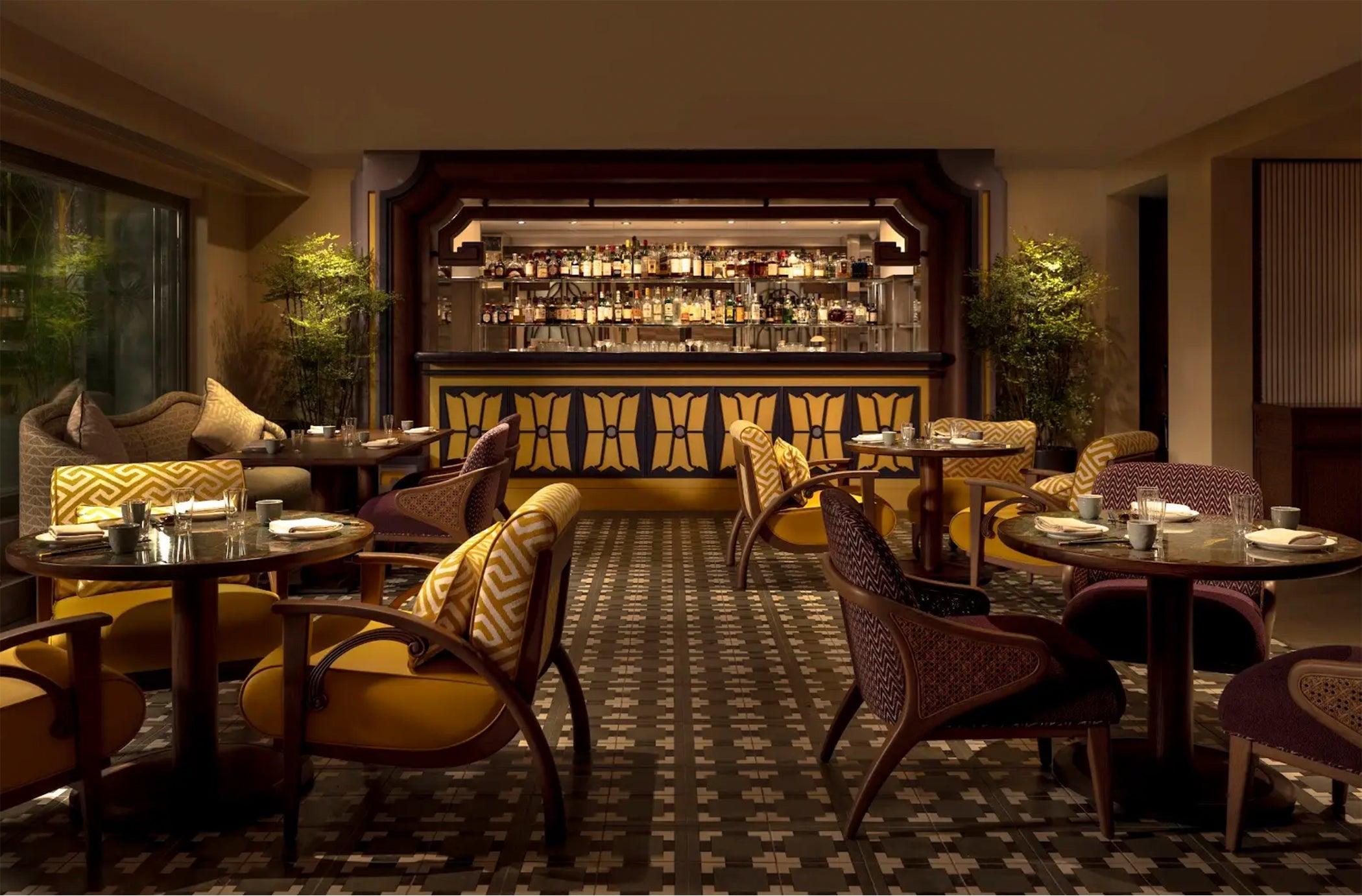 A dining room with a patterned floor, leather chairs and a lit bar at the back