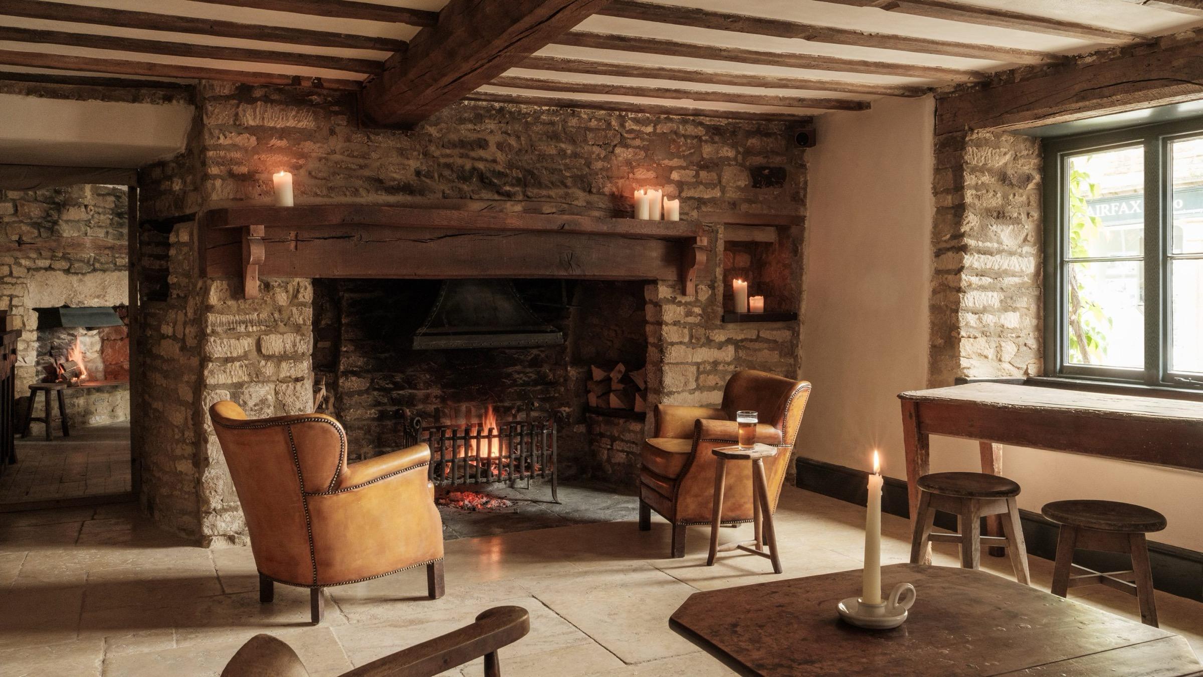 A stone-walled pub dining room with a fire lit in the hearth