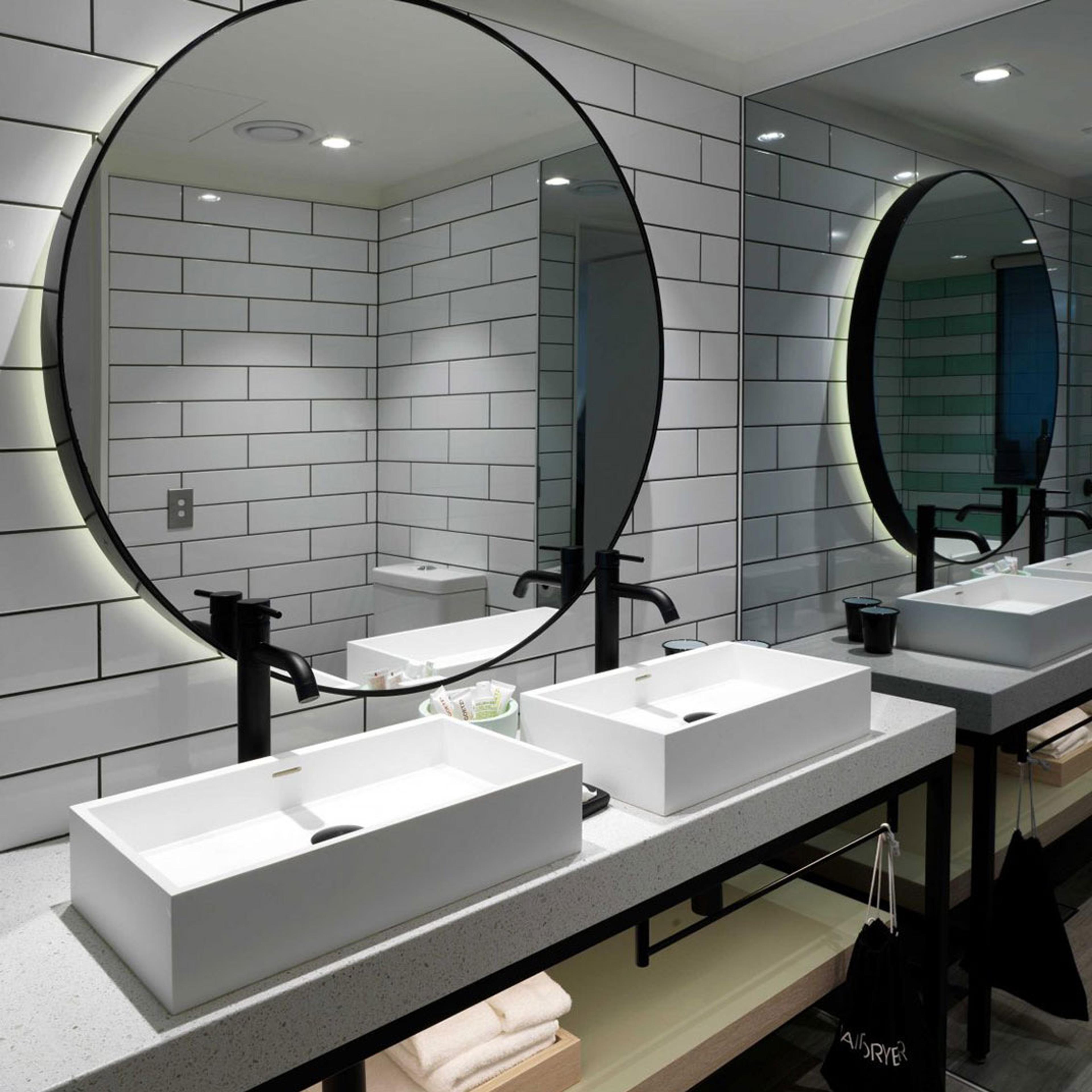 A bathroom with two round mirrors over twin basins
