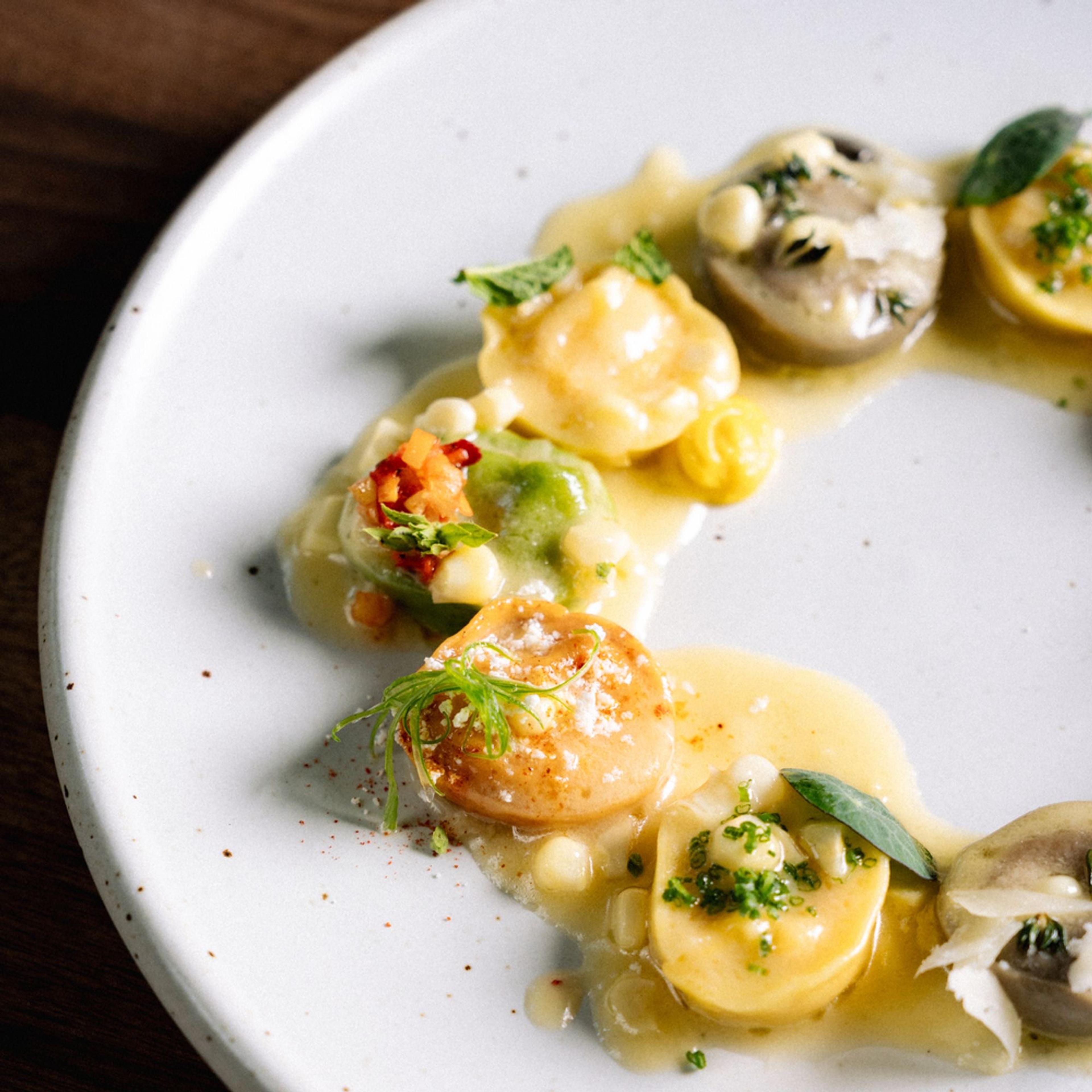Filled pasta in a light butter sauce with herbs and mushrooms on a white plate