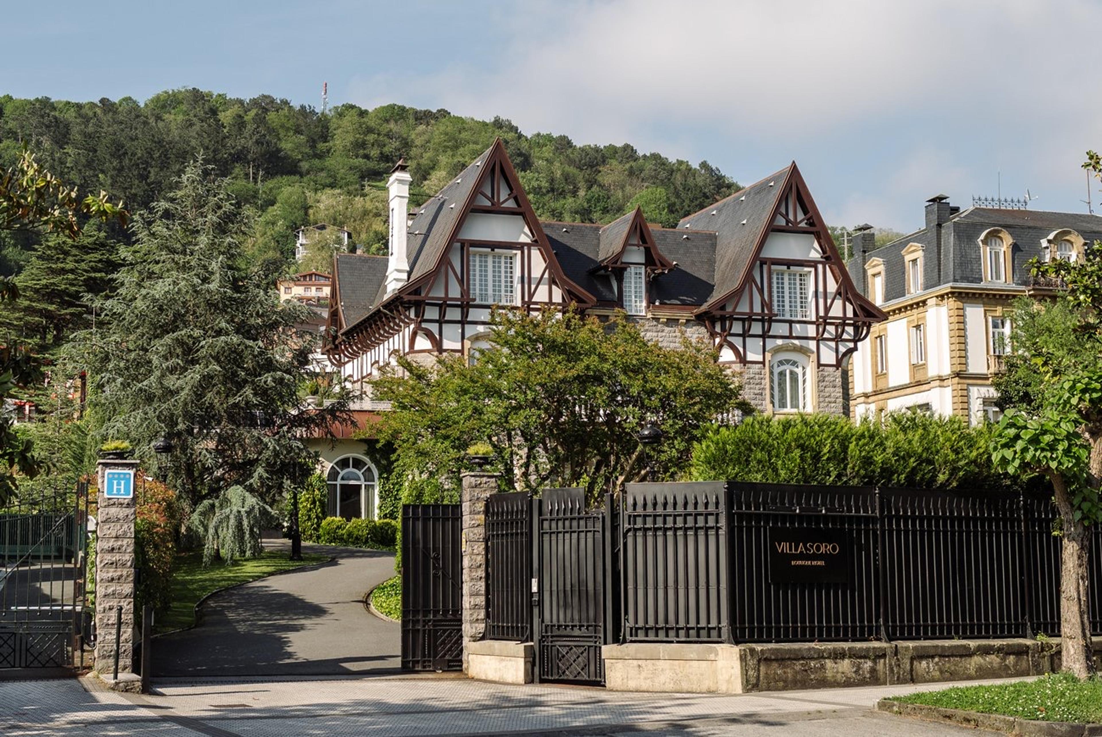 A wrought iron gate marked Villa Soro in front of the stone and timber villa, framed by trees.