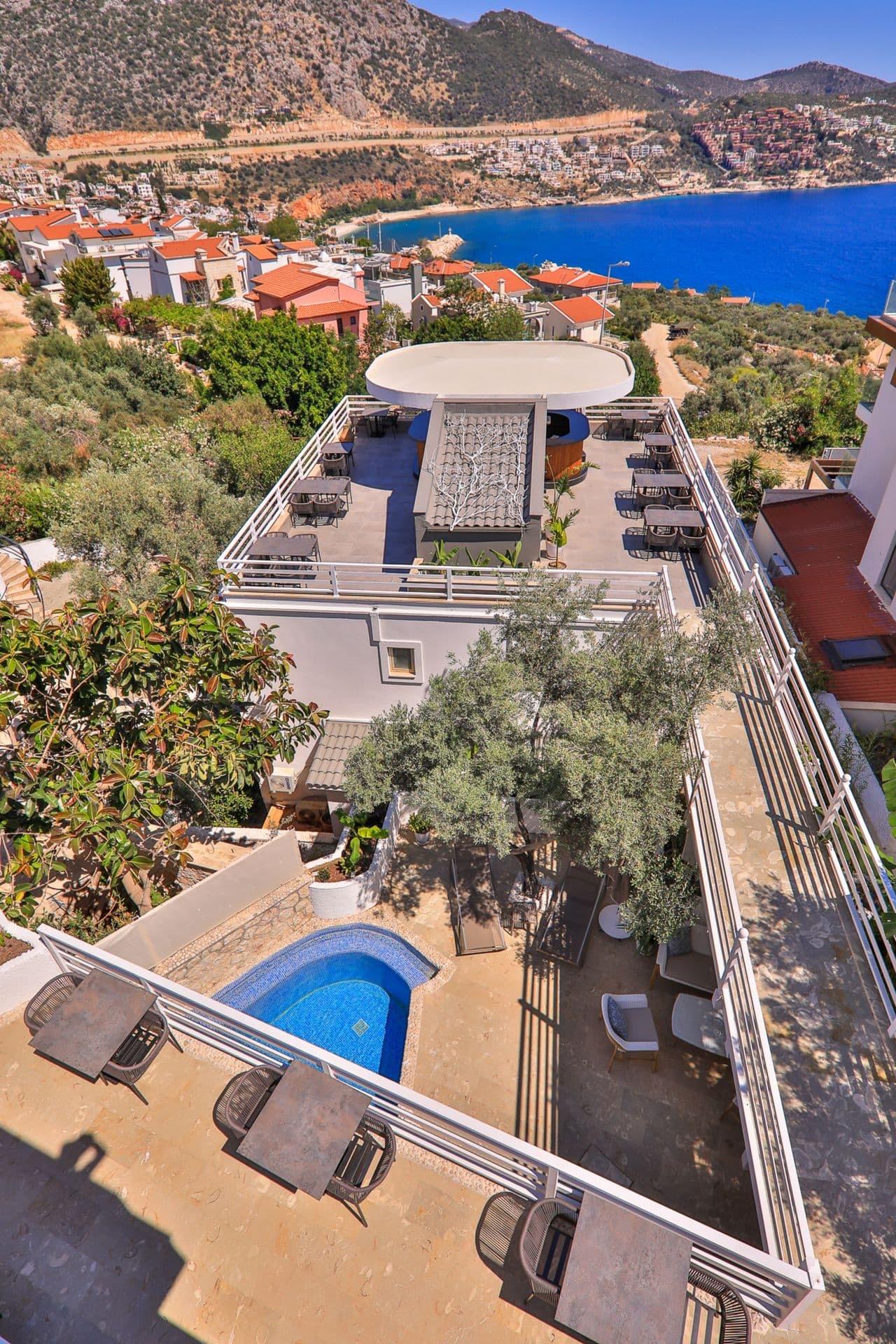 An elevated view of the hotel's rooftop terrace and a small pool, with the town and bay spread out beyond.