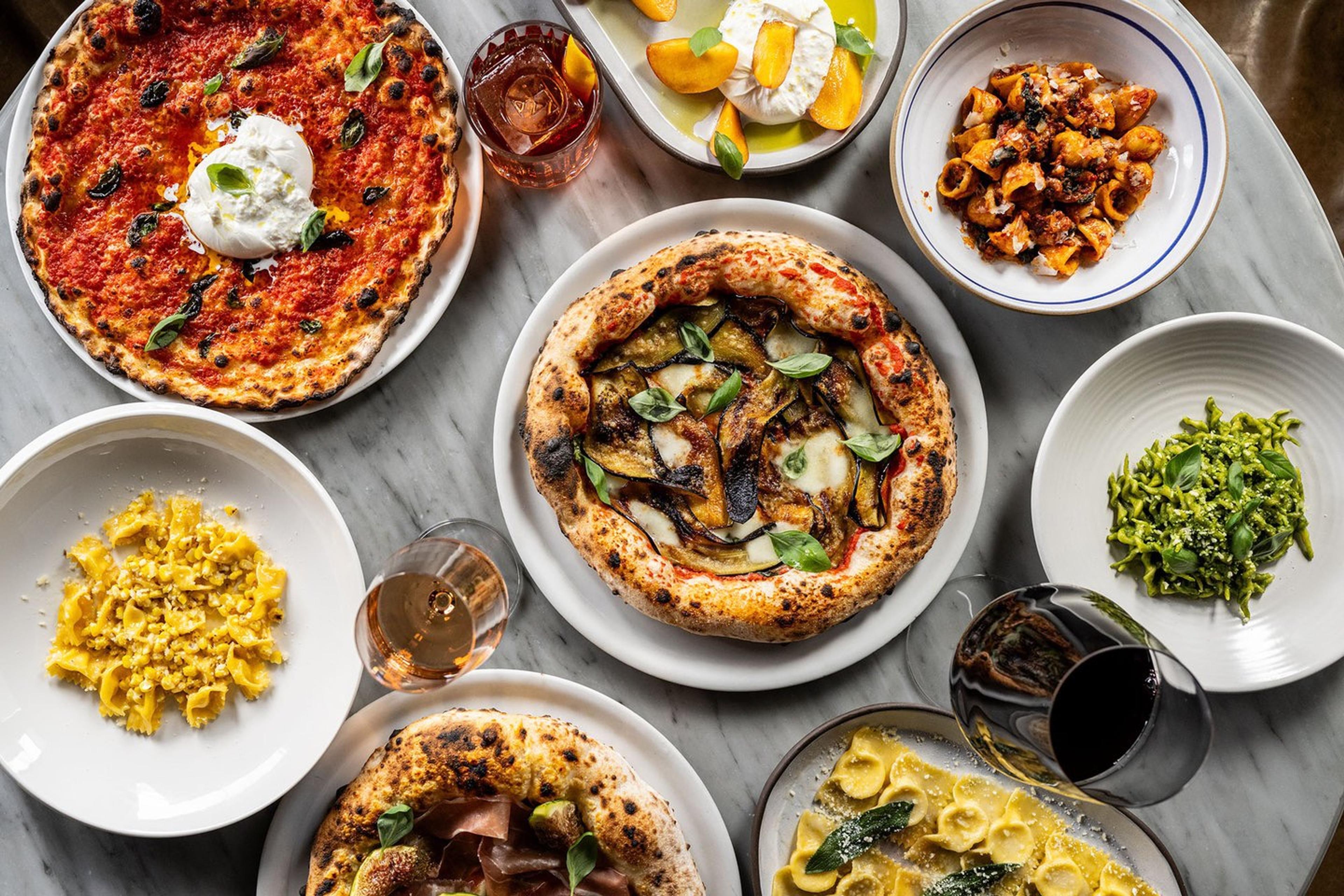 A spread of Felix's pasta, pizza and small plates on a grey table, seen from above