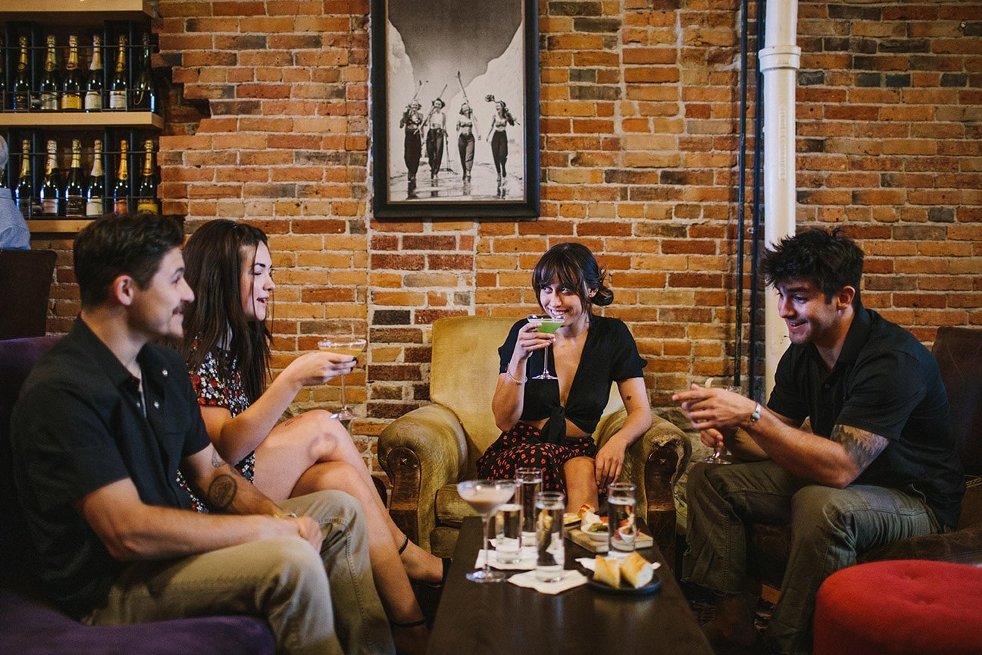 Friends round a low table of wine glasses against an old brick wall
