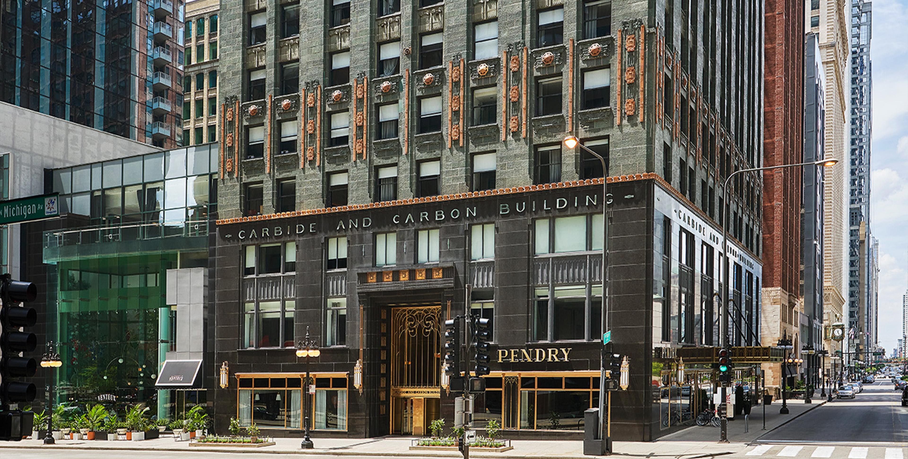 The stone and bronze facade of the Carbide and Carbon Building at street level, with the Pendry name lit above the entrance.