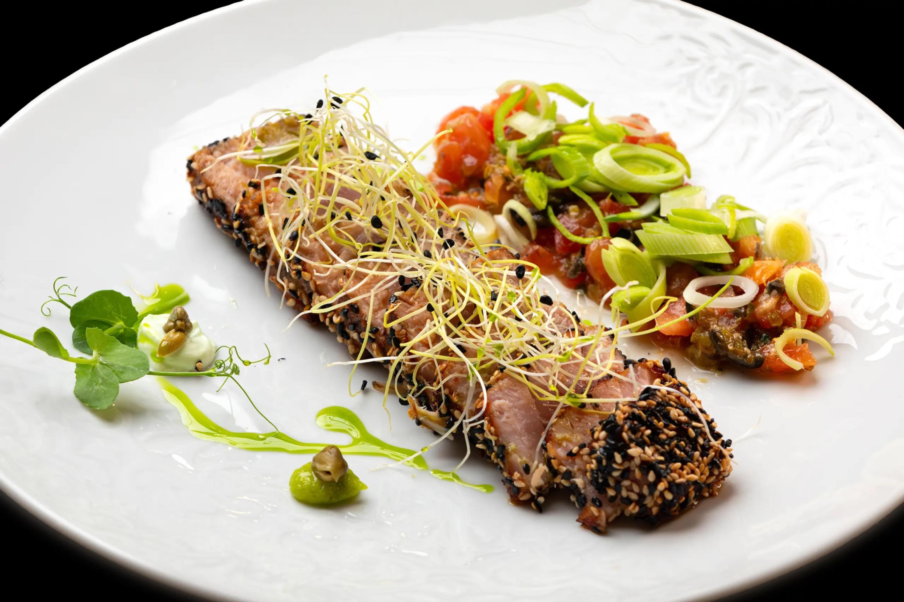 A sliced seared fillet with herbs on a white plate