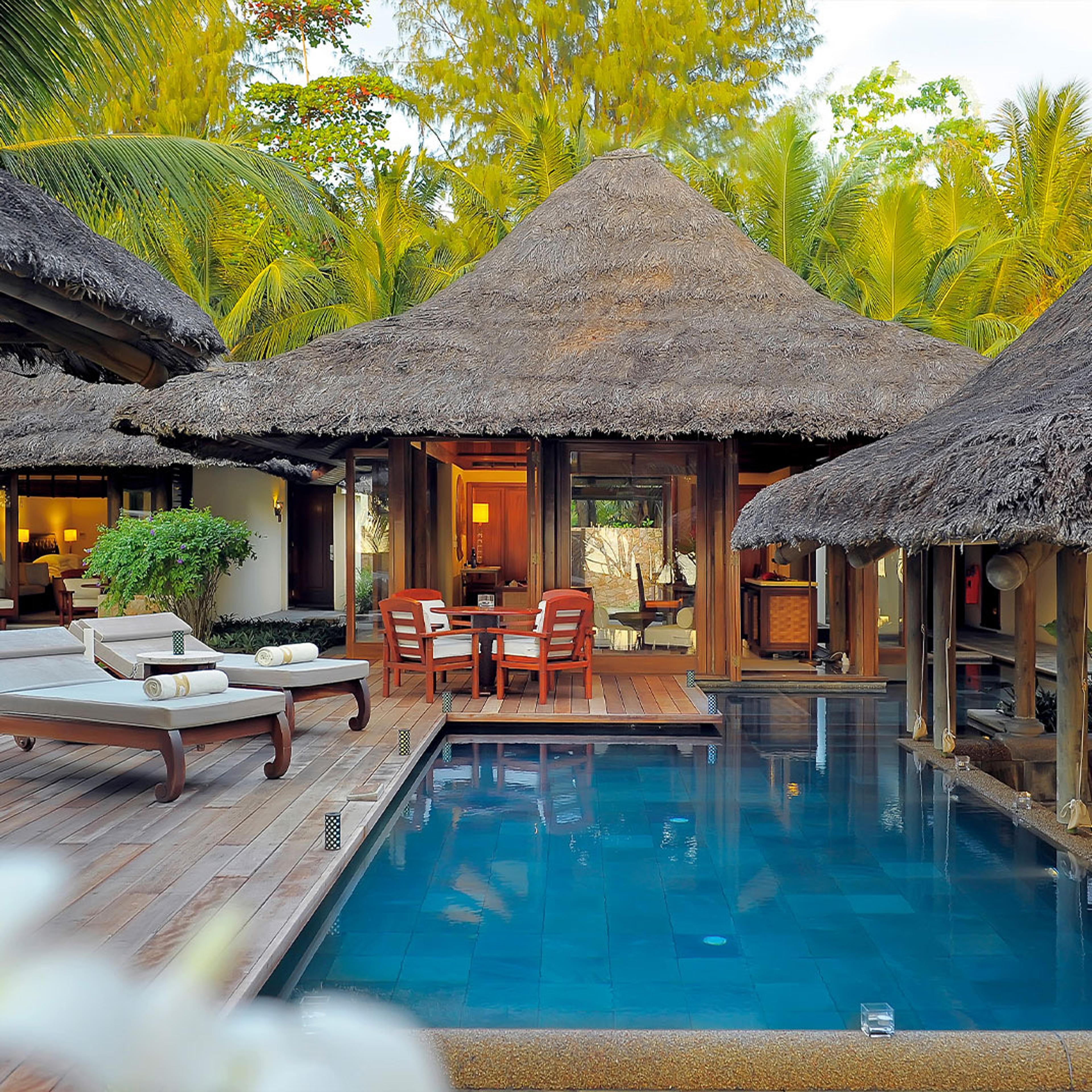 A villa's pool beside thatched roofs