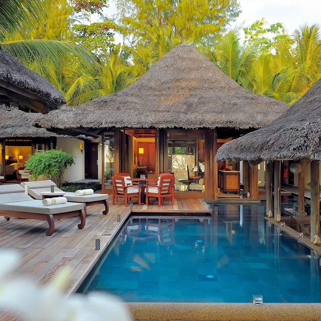A villa's pool beside thatched roofs