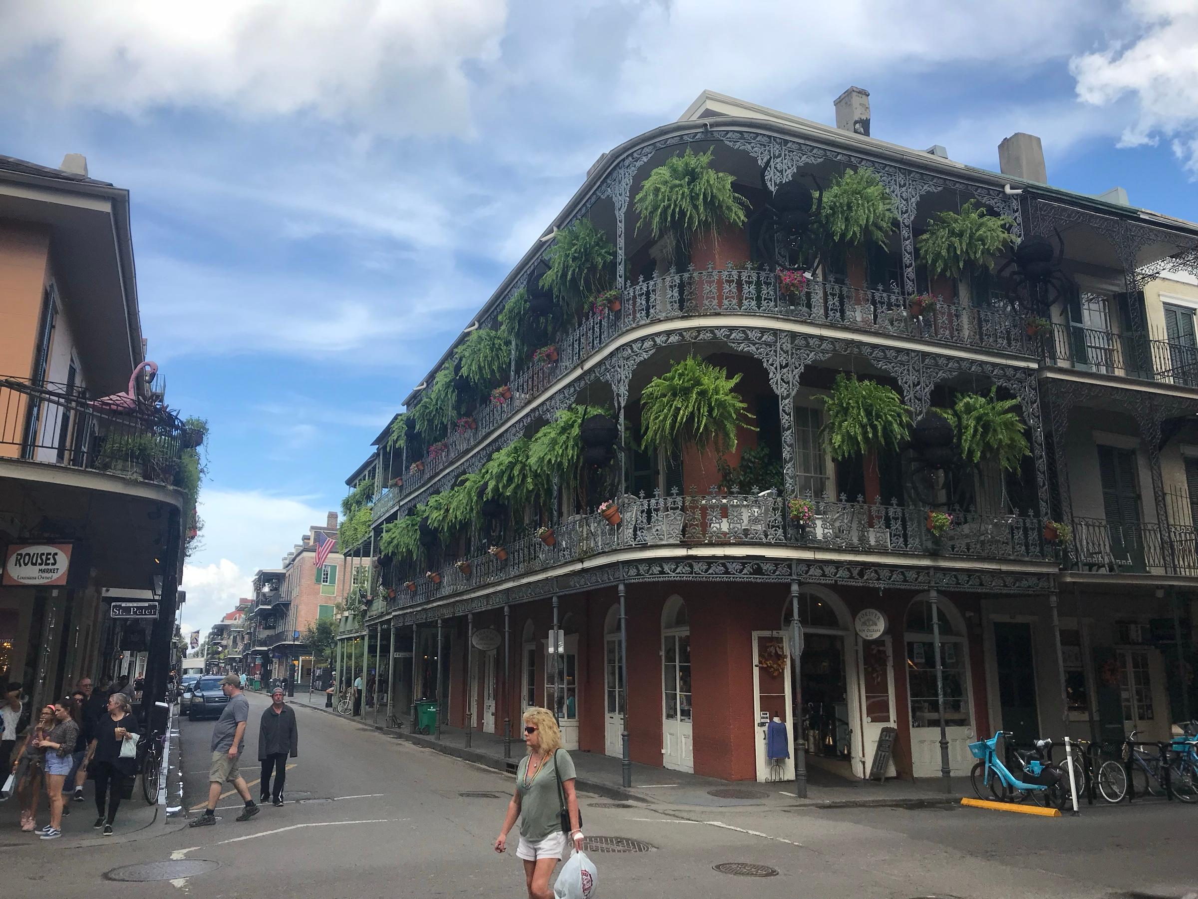 Iron-lace balconies hung with ferns on a street corner in the French Quarter of New Orleans