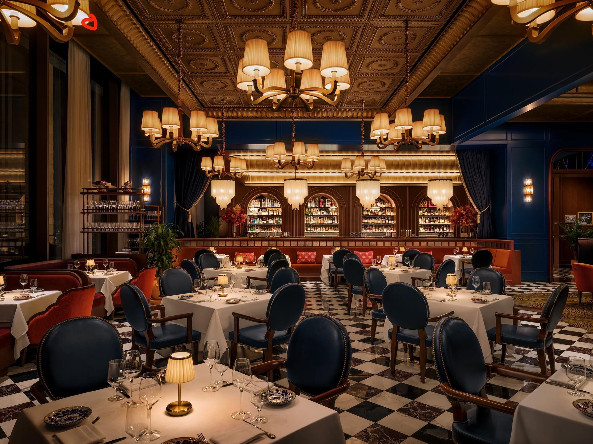 Carbone's dining room at Atlantis The Royal, chandeliers over a chequered marble floor and blue leather chairs