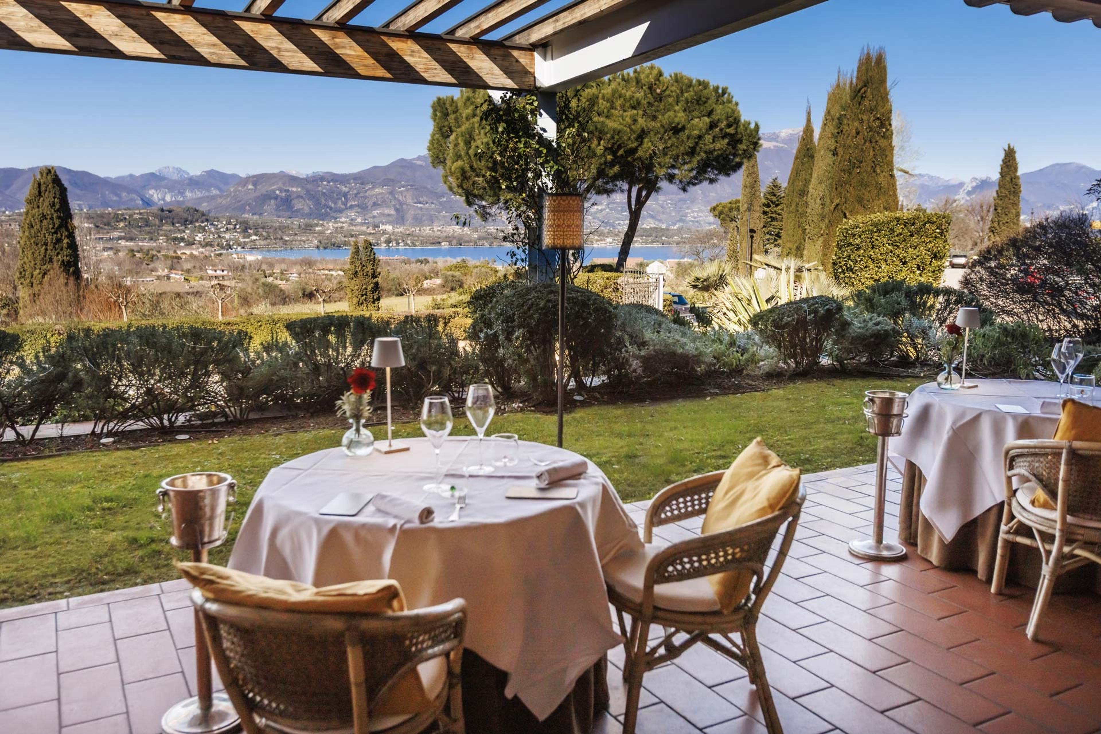 Tables on a terrace above the lake, cypresses and the far shore beyond