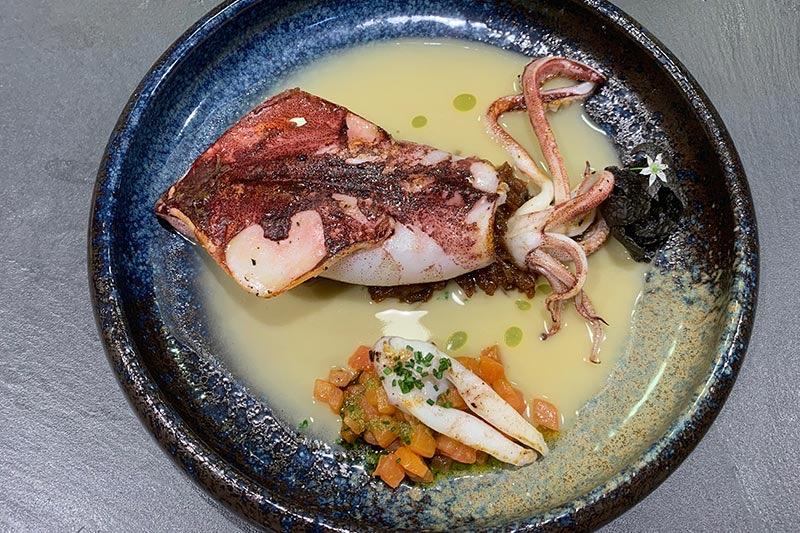Squid and fish in a pale sauce in a deep blue bowl at Casa Urola