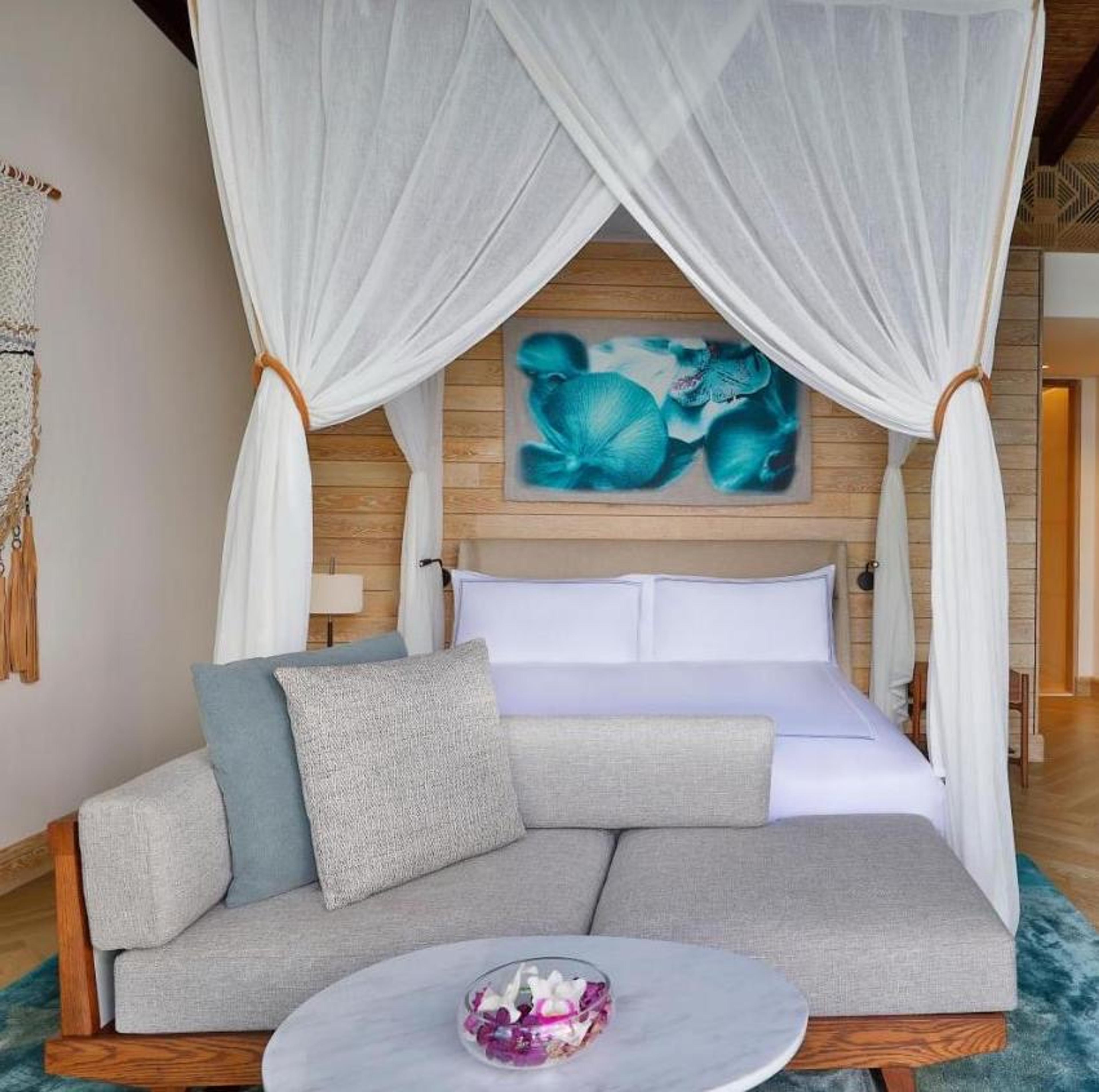 A canopy bed under a blue painting