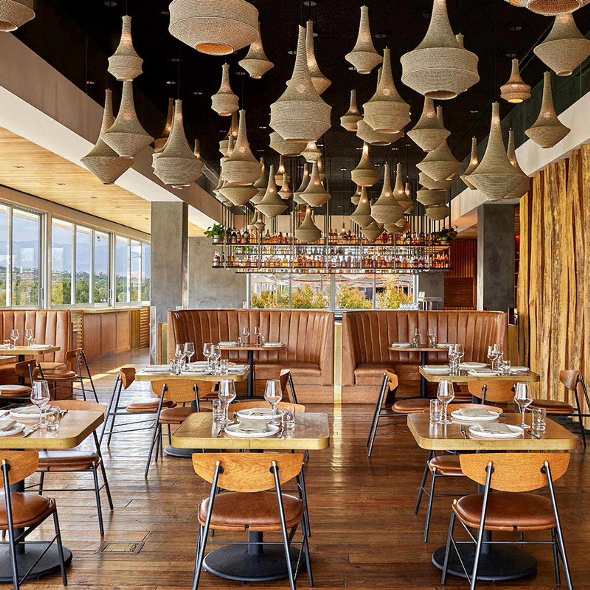 A dining room of leather banquettes under hanging lamps, with windows onto the mountains