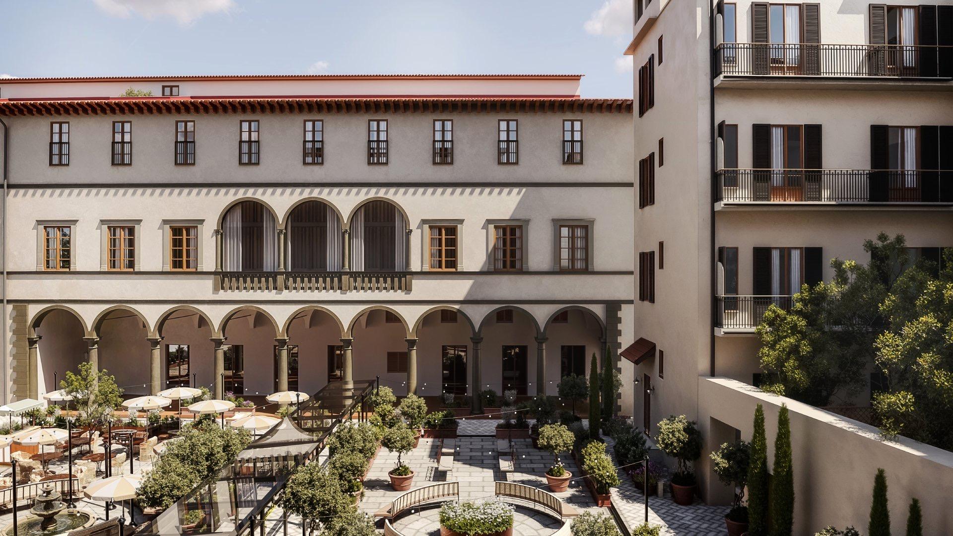 An elevated view of a Renaissance palazzo courtyard with an arched loggia, terracotta roof tiles, and a terrace of umbrellas, potted citrus trees and dining tables below.