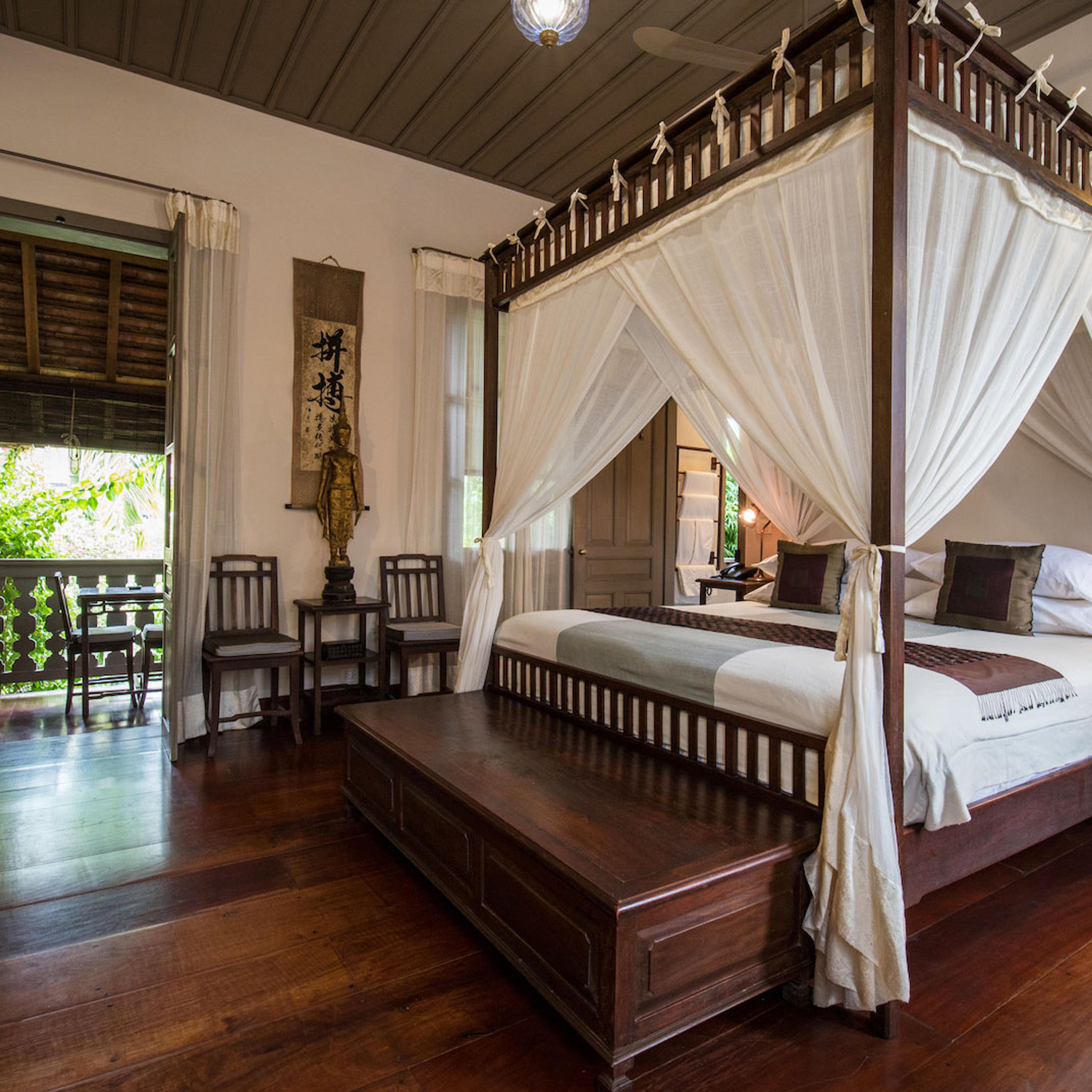 A four-poster bed hung with nets in a wood-floored room