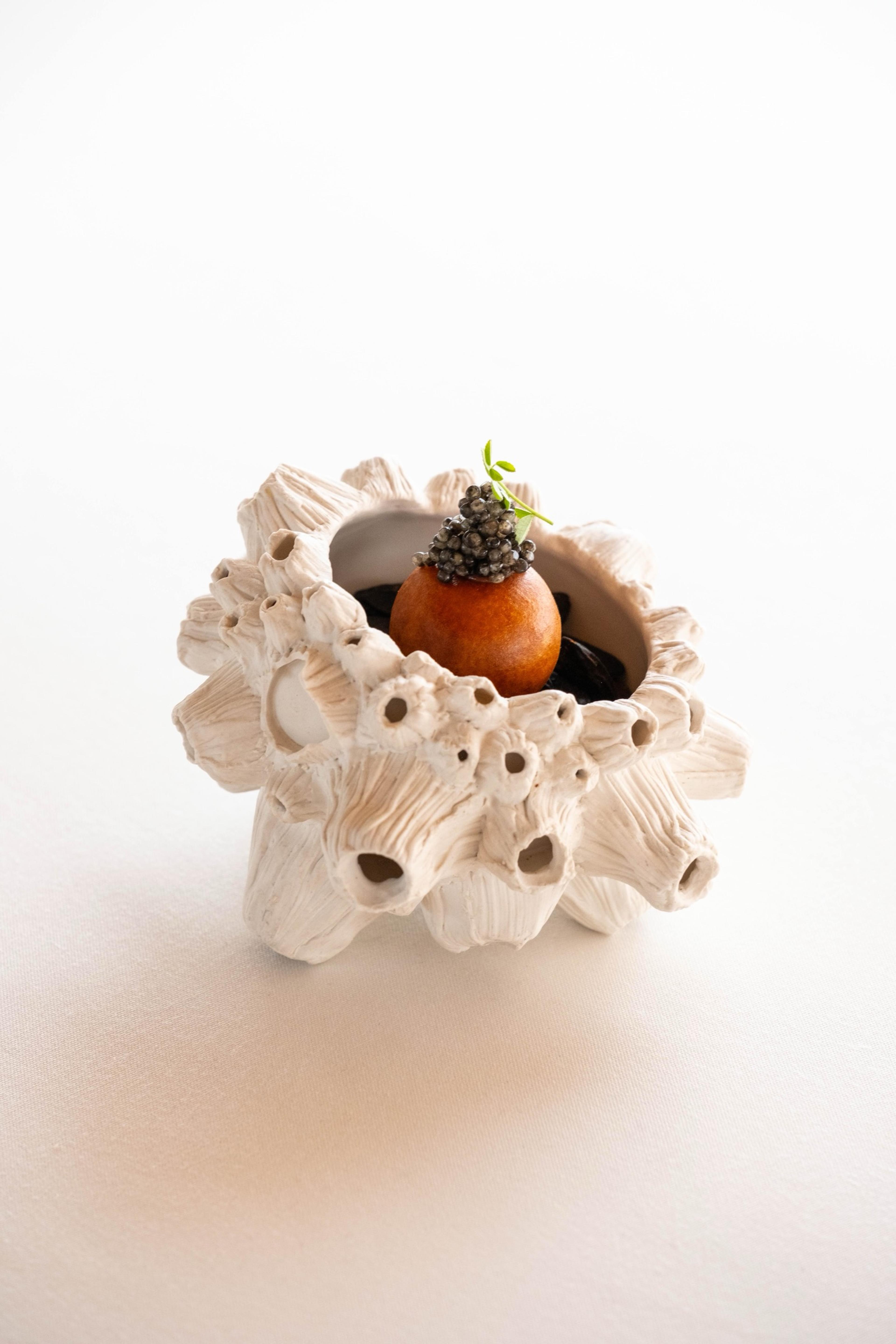 A small dish served in a white, coral-like ceramic bowl