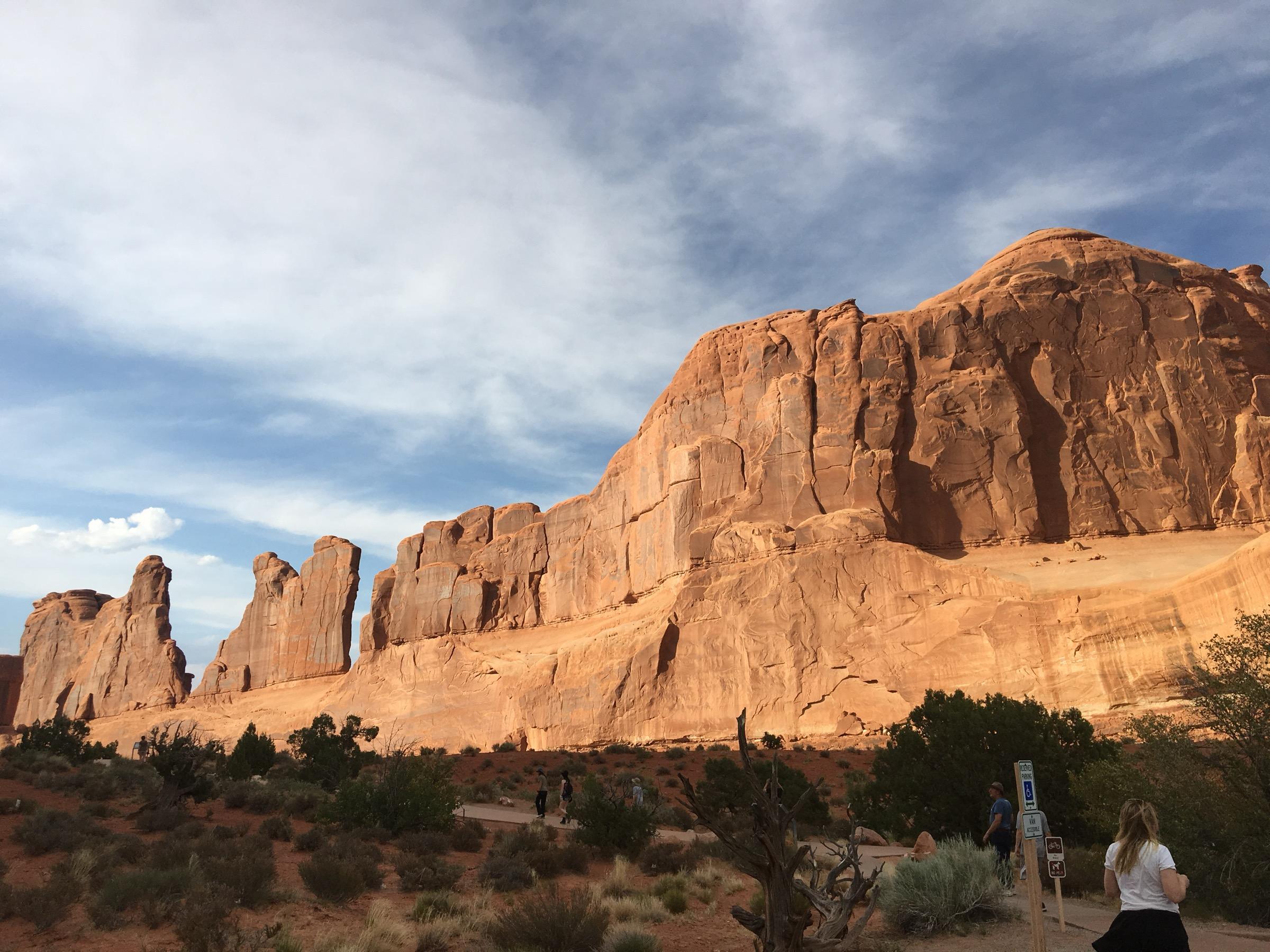 The sandstone walls of Park Avenue in Arches National Park, lit red in the evening under a streaked sky