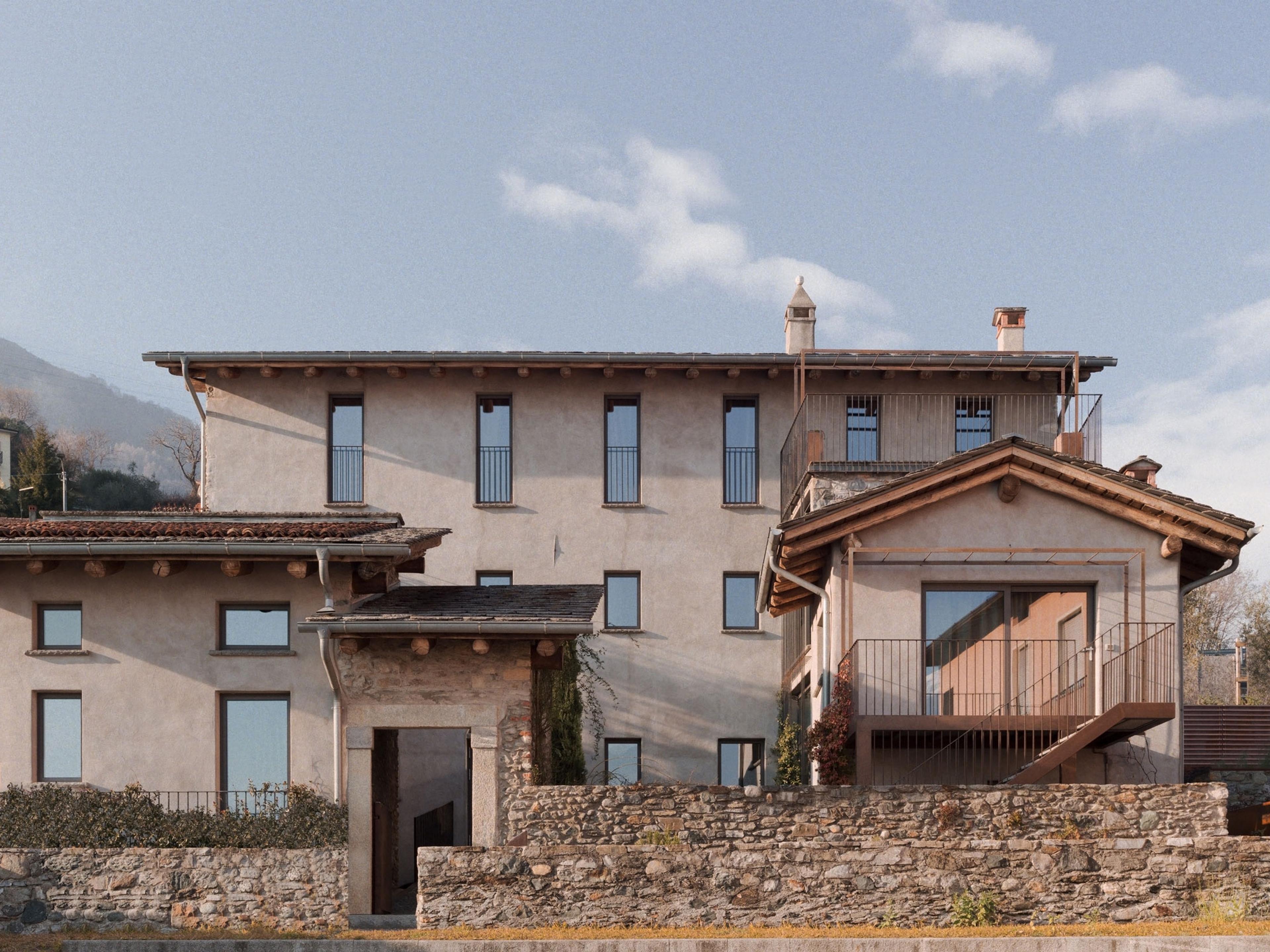 the full stone and stucco building under a blue sky with scattered cloud, seen from the garden