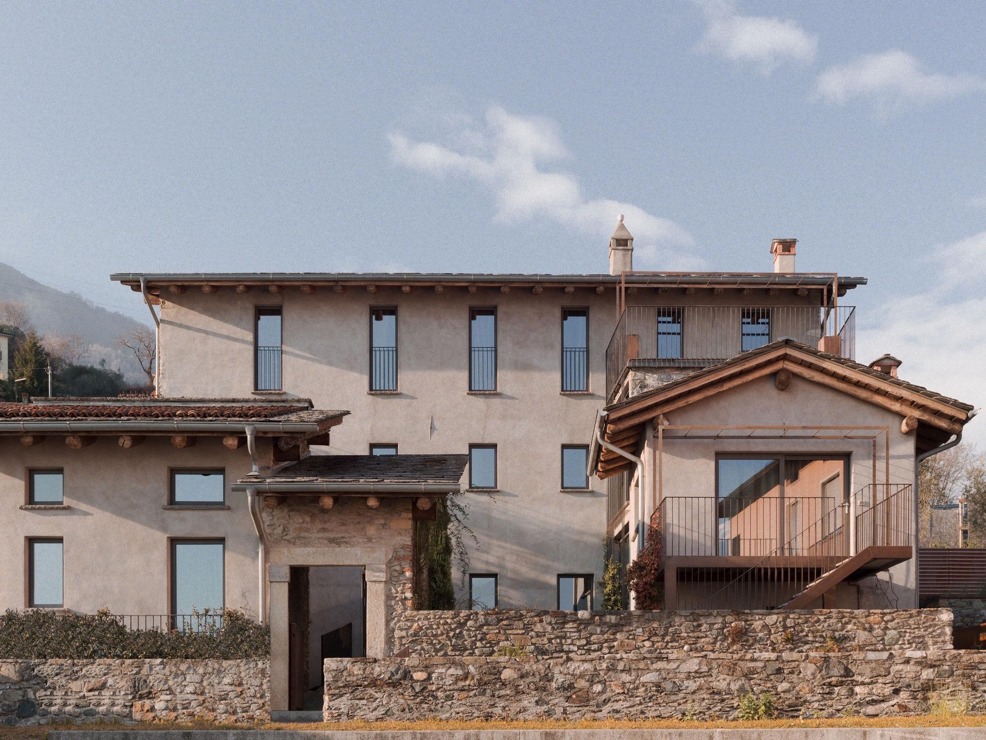 the full stone and stucco building under a blue sky with scattered cloud, seen from the garden