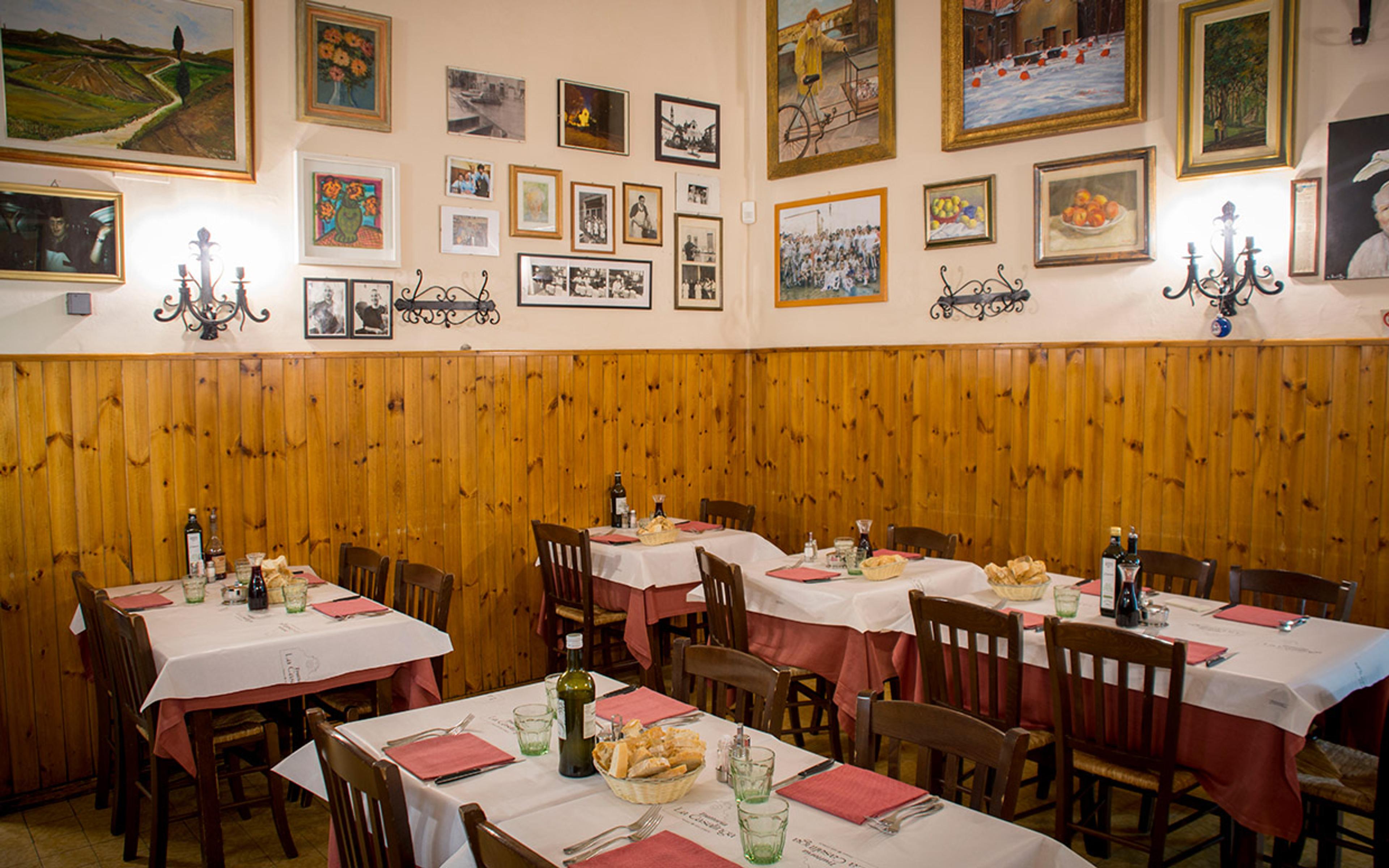 The dining room at Trattoria La Casalinga, tables in red and white cloths under walls hung with pictures
