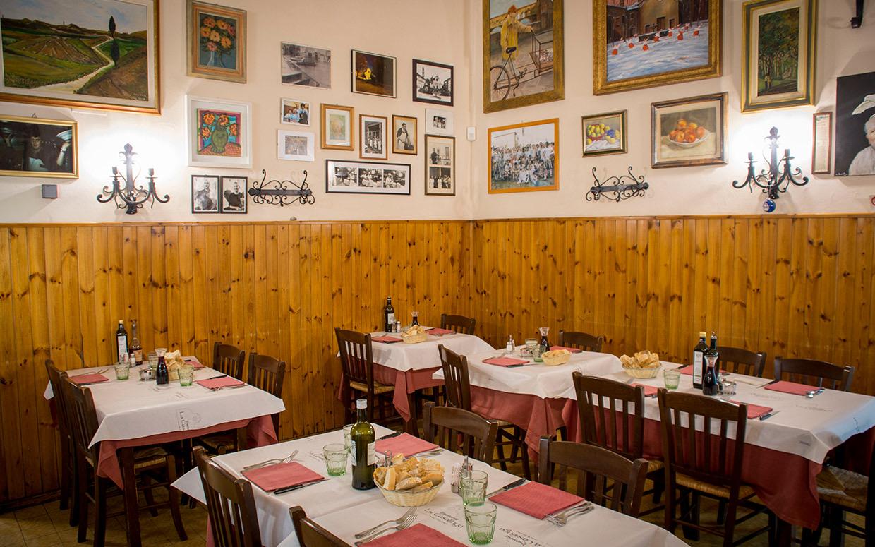 The dining room at Trattoria La Casalinga, tables in red and white cloths under walls hung with pictures
