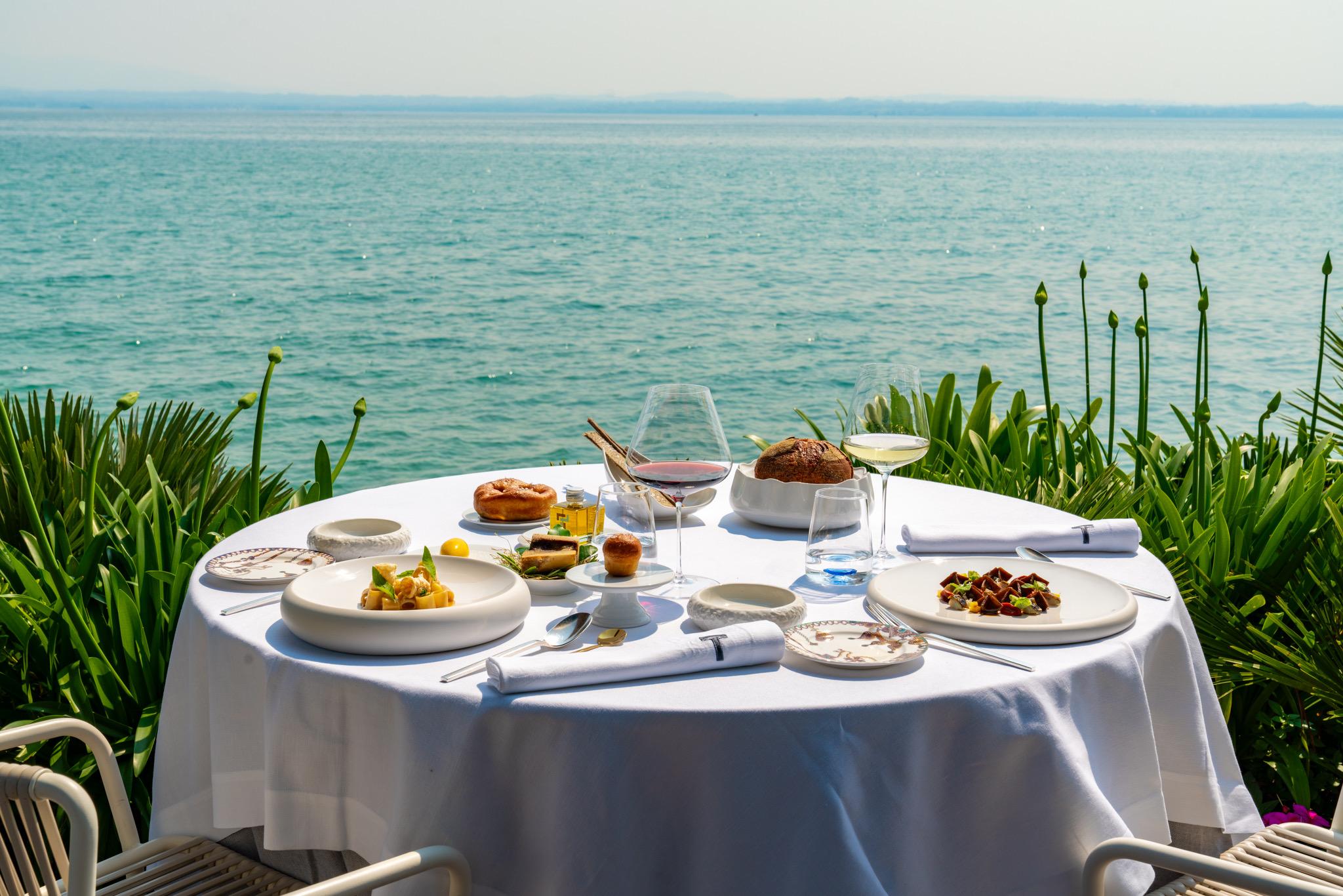 A table laid in white at the water's edge, the lake running out to the horizon