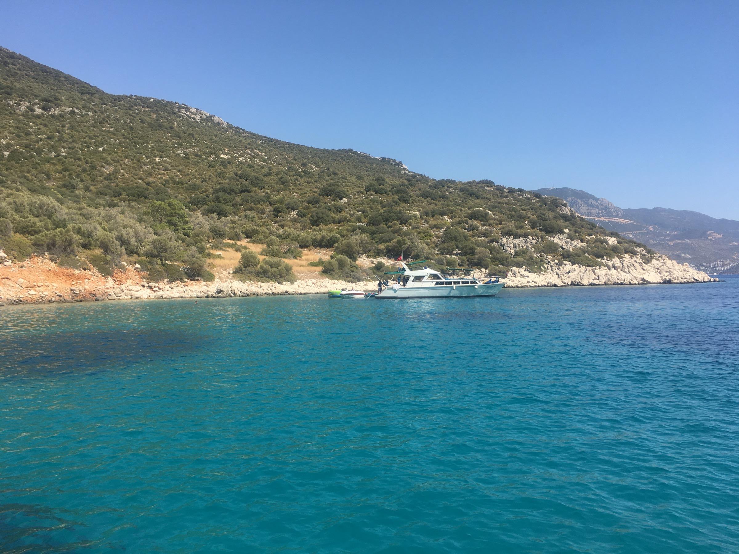 Turquoise water in a bay near Kalkan, a motor yacht moored under hills of scrub and pale rock