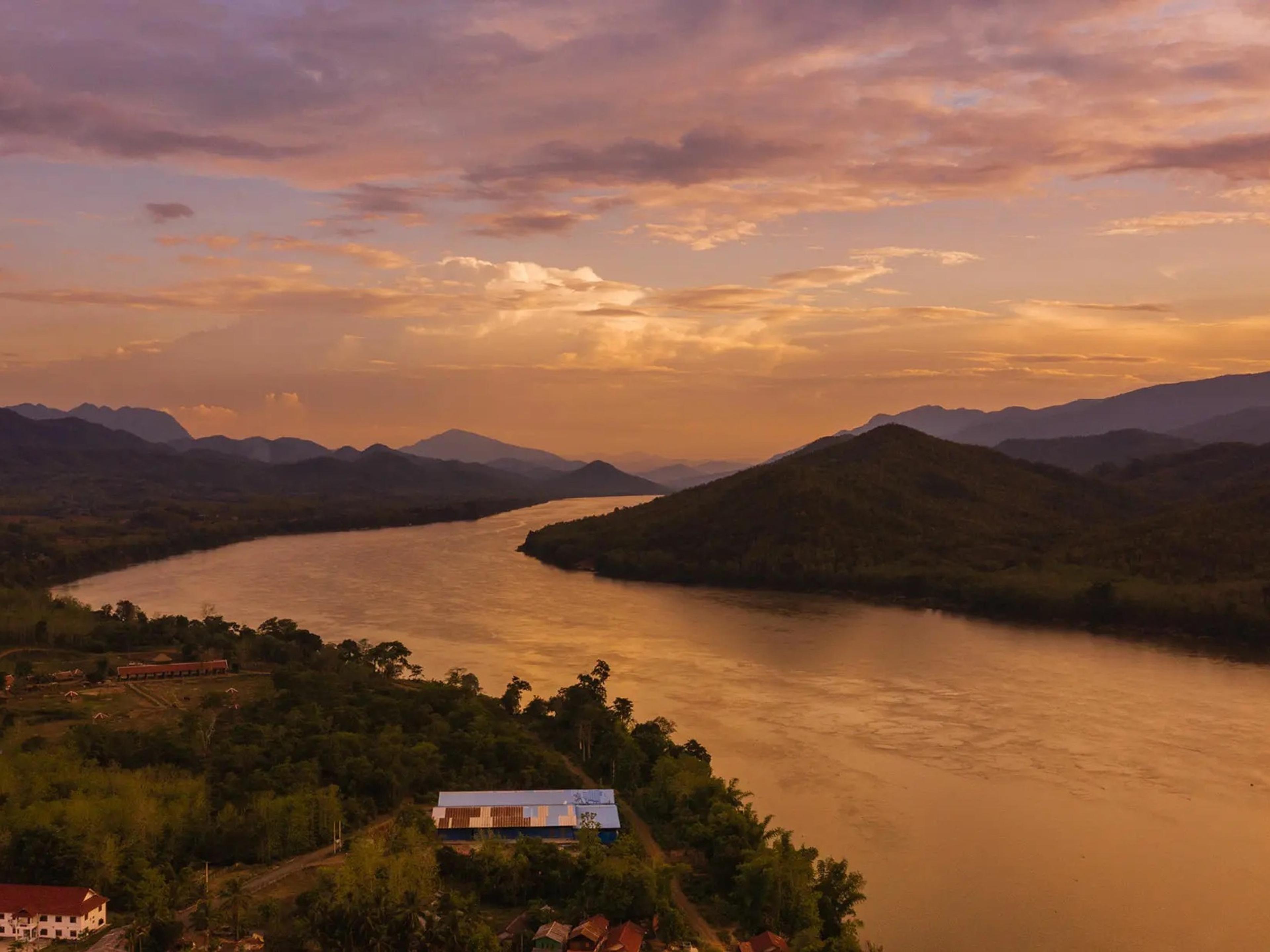 The Mekong at sunset, winding between forested hills