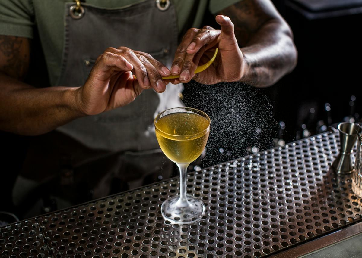 A bartender at Death & Co finishing a cocktail over the bar