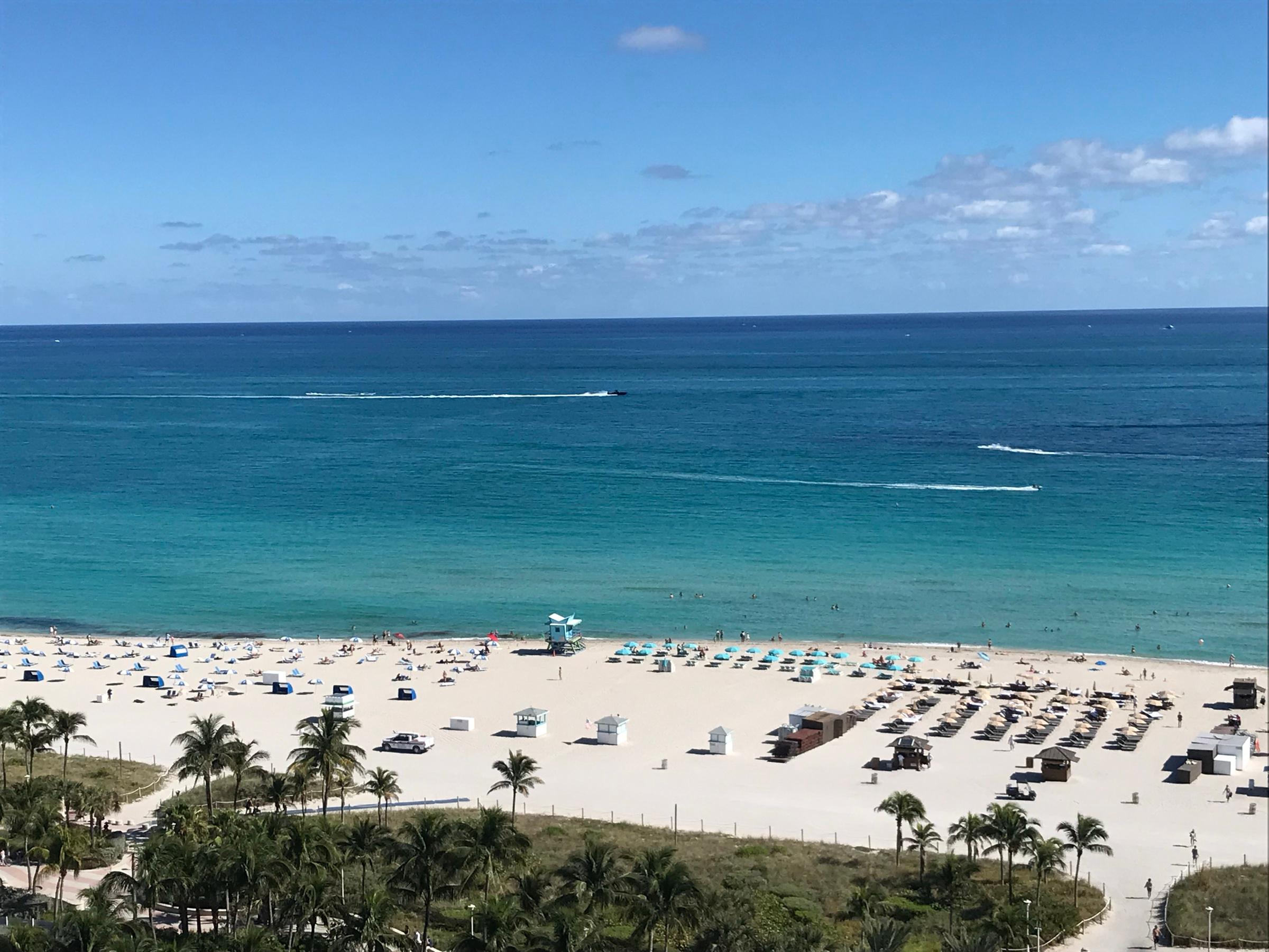 Miami Beach from above, rows of loungers on white sand and turquoise water beyond