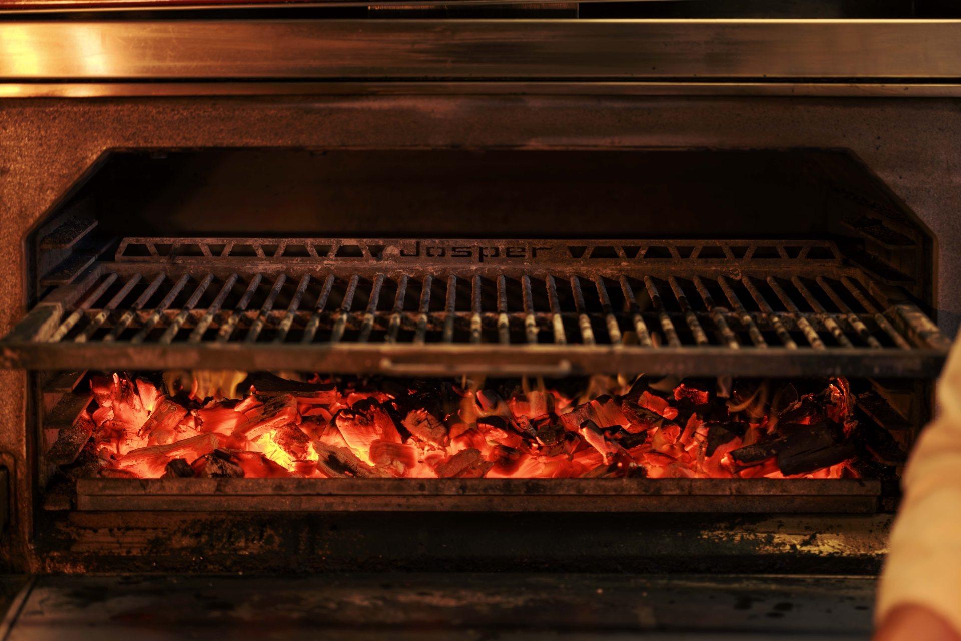 A charcoal grill glowing red beneath its cooking rack