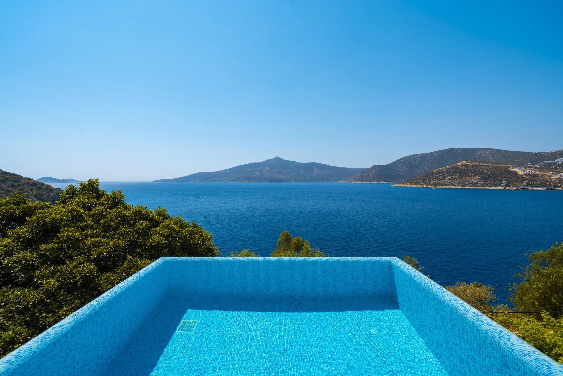 A plunge pool on a rocky ledge, with the sea, a distant island and hills beyond.