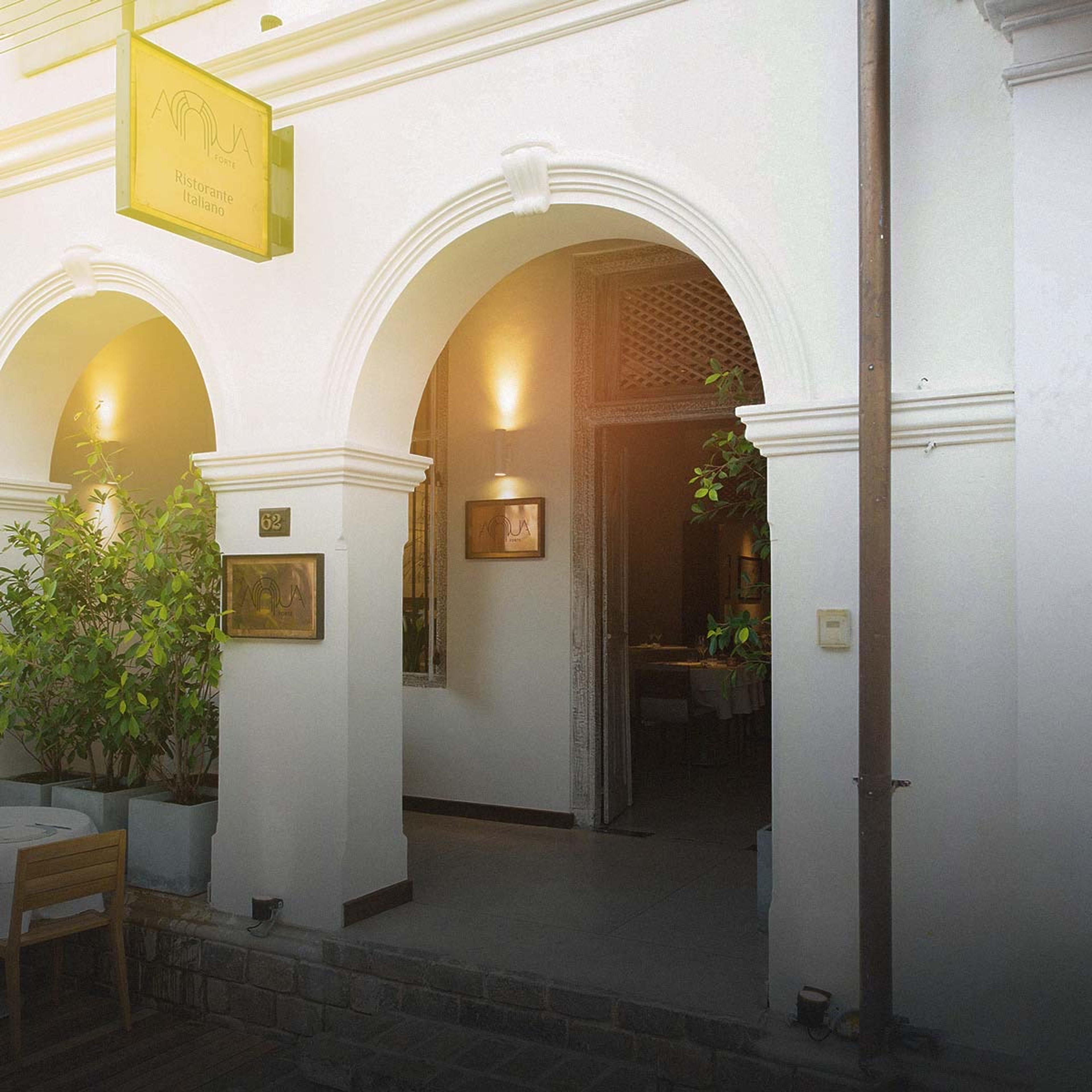 White arches along the front of an old house in Galle Fort, its doors open on a lit room