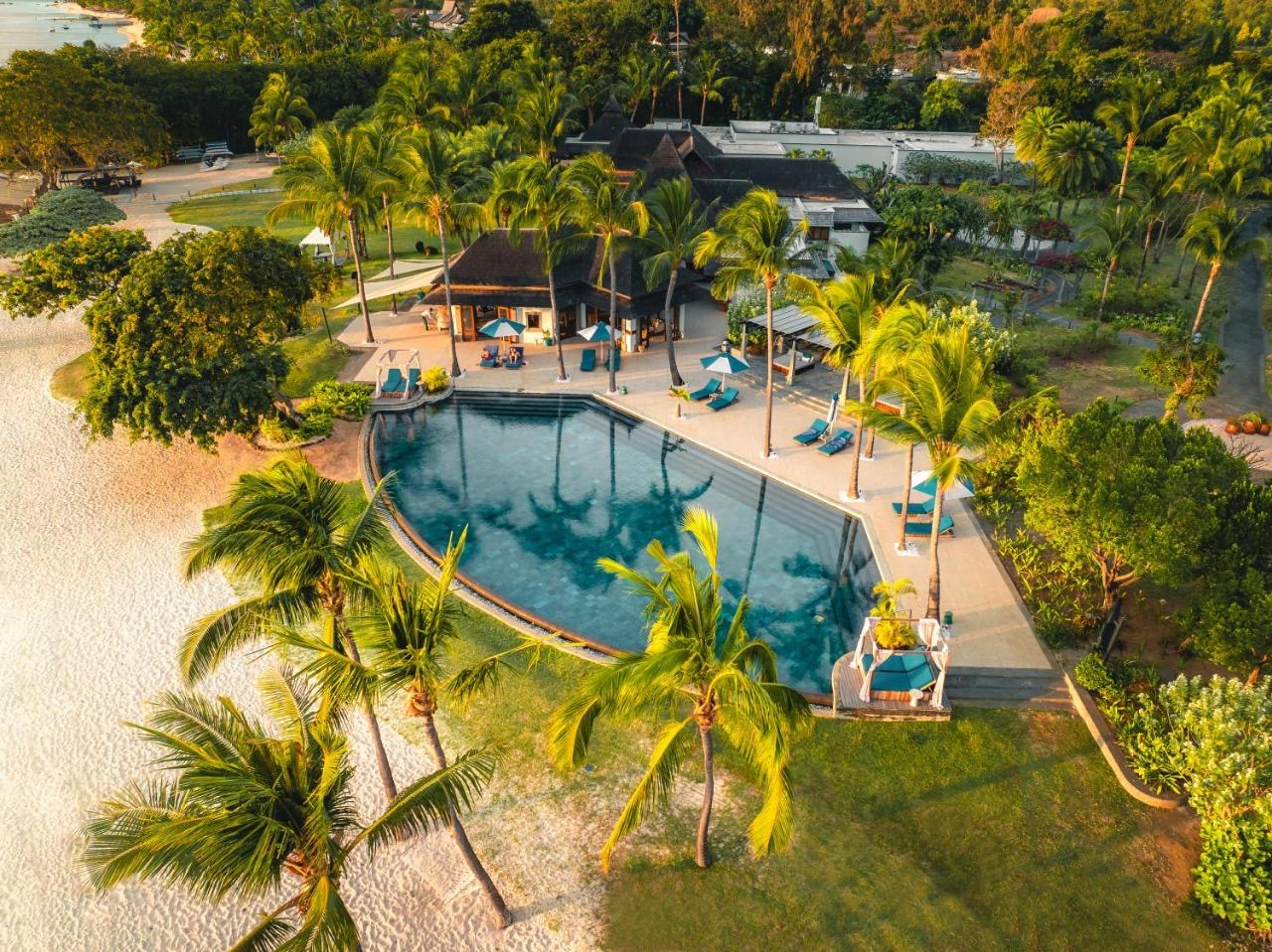 The resort from above, a pool among palms by the sea