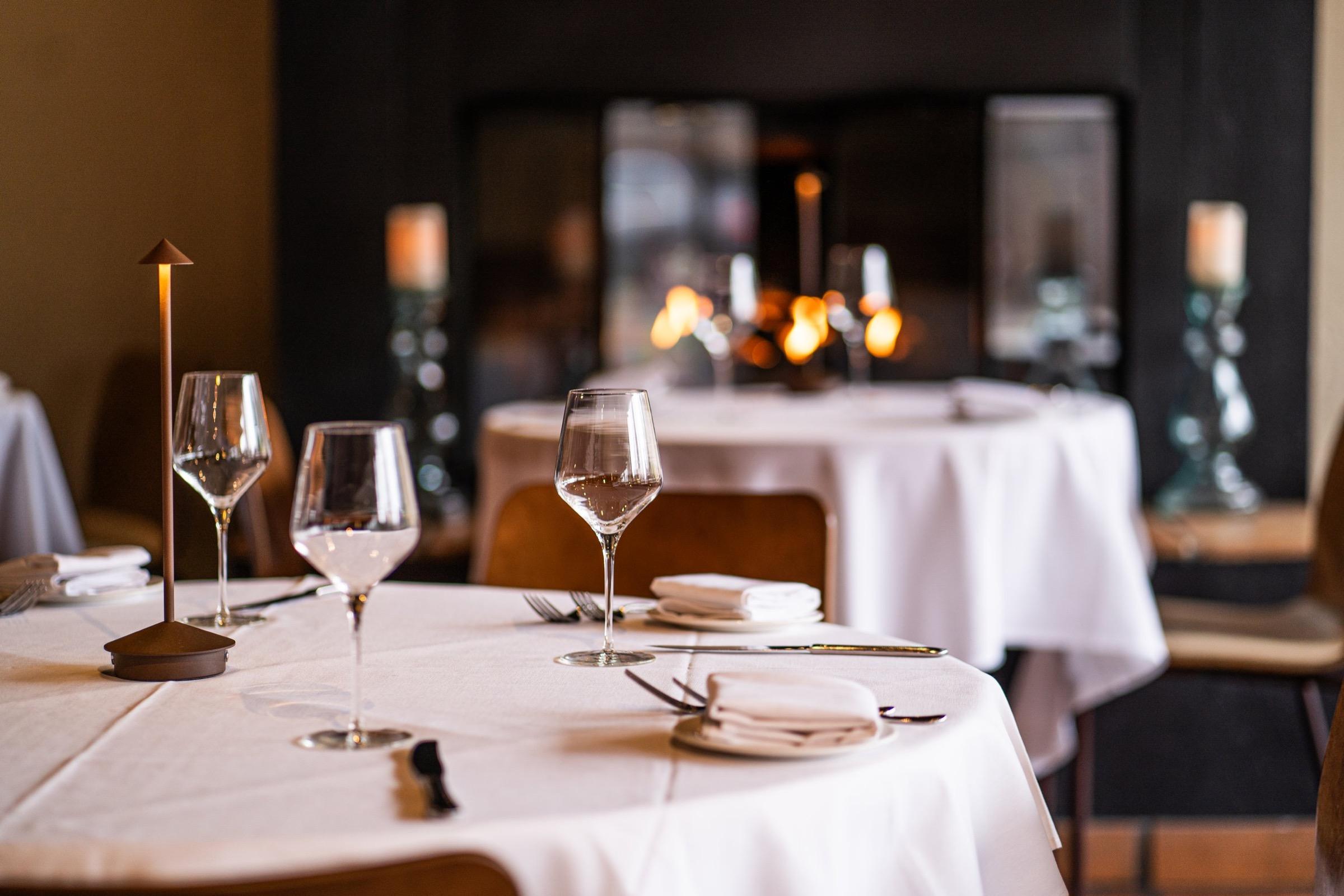 A table laid for dinner at Barolo Grill, glasses on a white cloth by candlelight