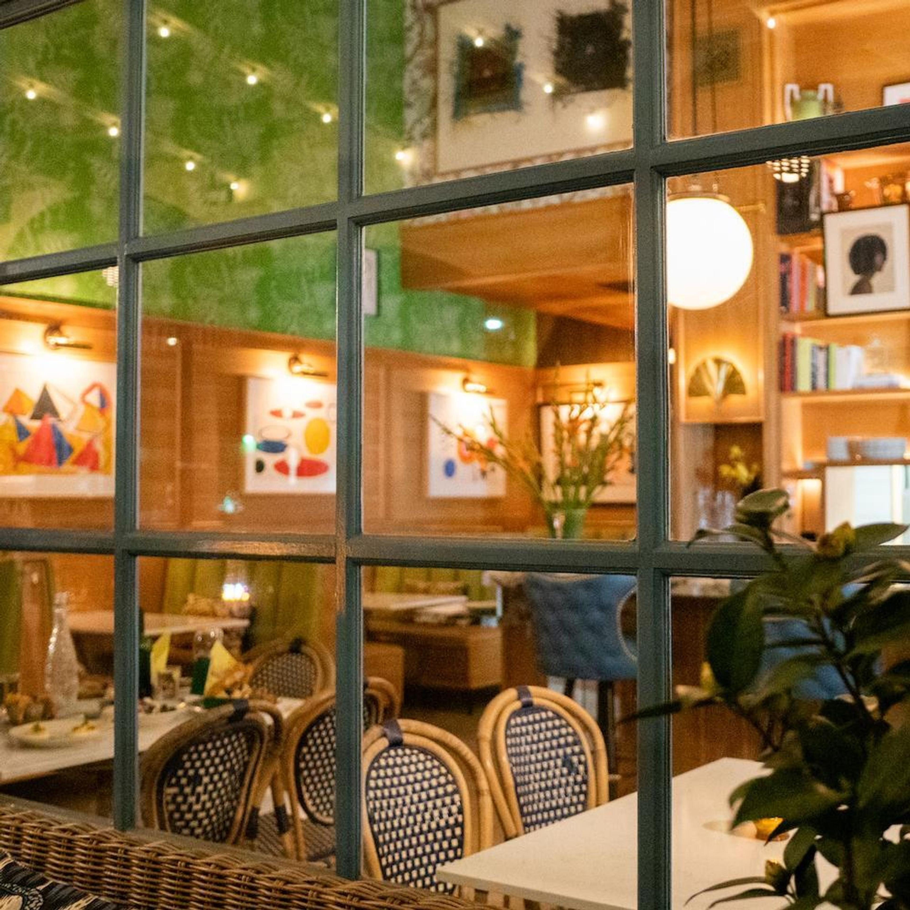 A wood-panelled dining room hung with modern art, seen through a window