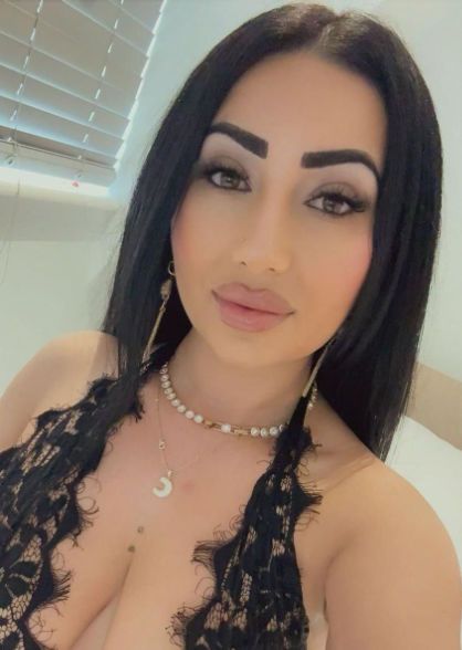 Raysa posing in a laced black top