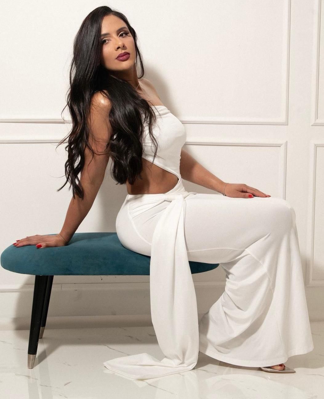 Patricia posing in a white dress looking over her should with long brunette hair