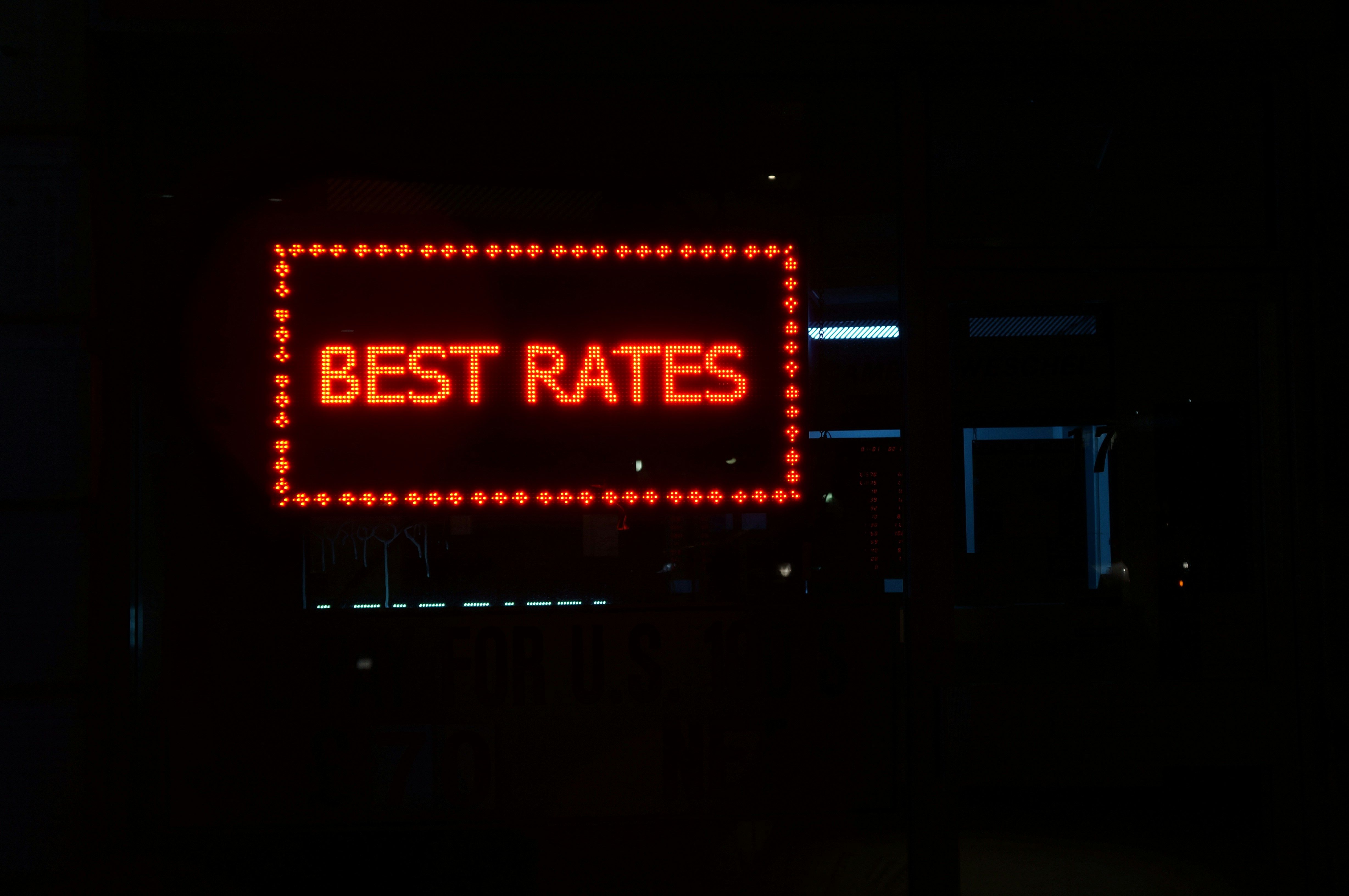 Orange neon sign that says best rates in a dark setting.