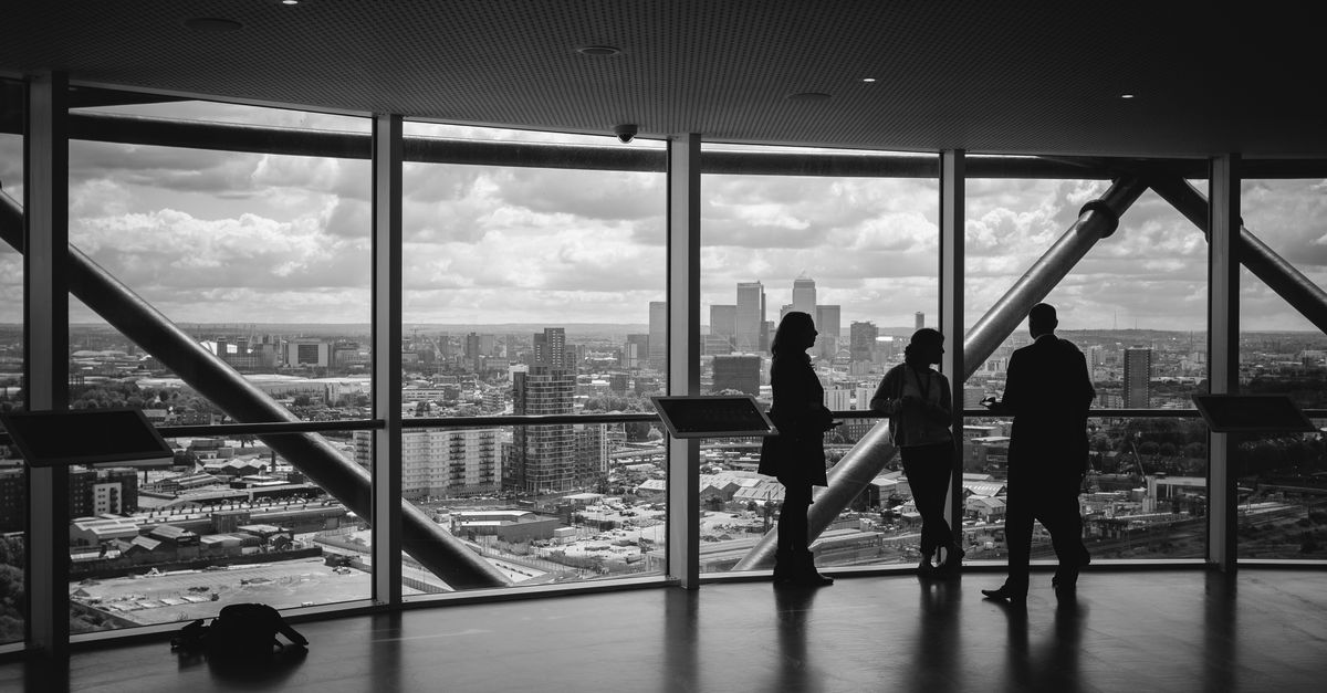 Three individuals looking over view of a city in the background.
